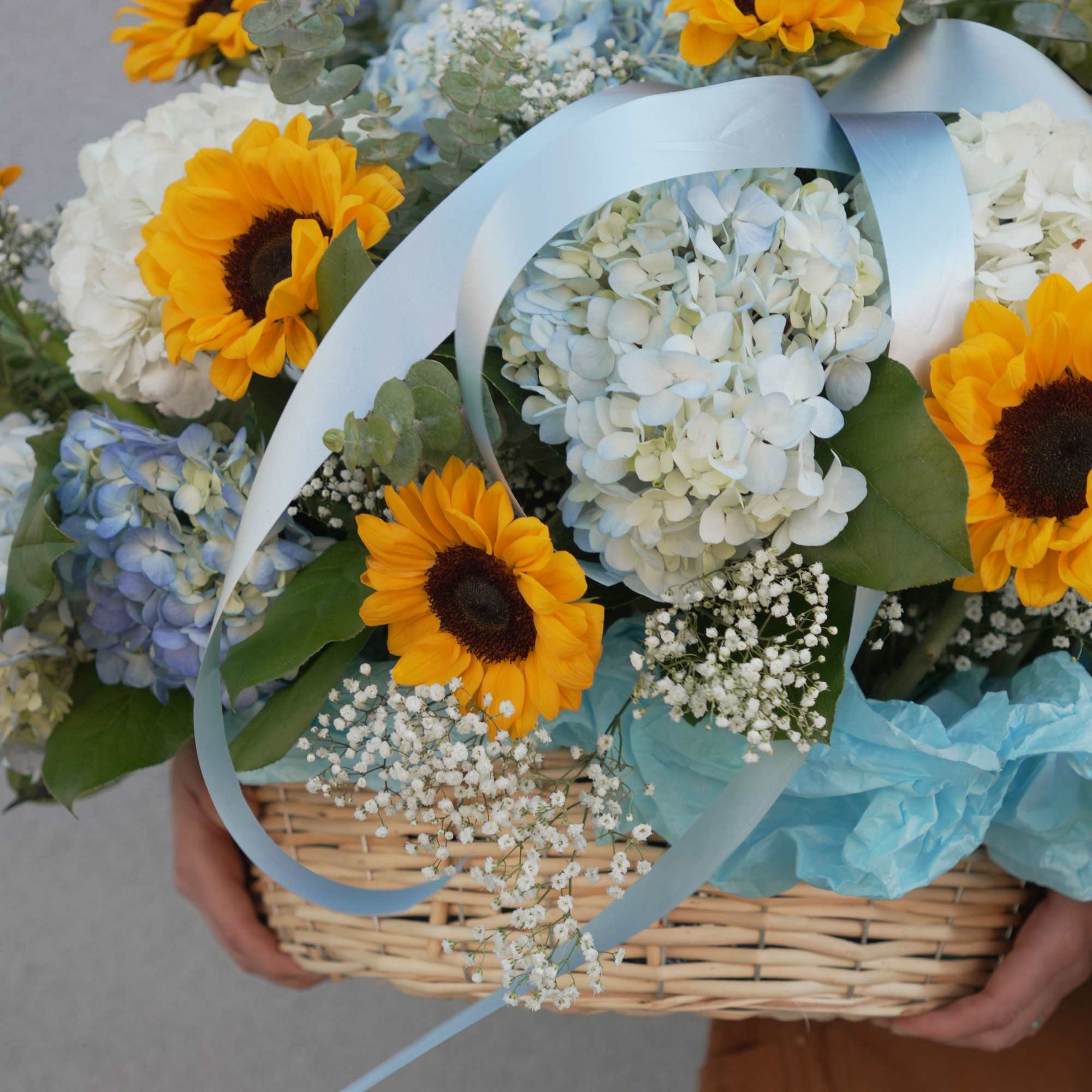 Bright yellow sunflowers take center stage in this cheerful flower arrangement, paired