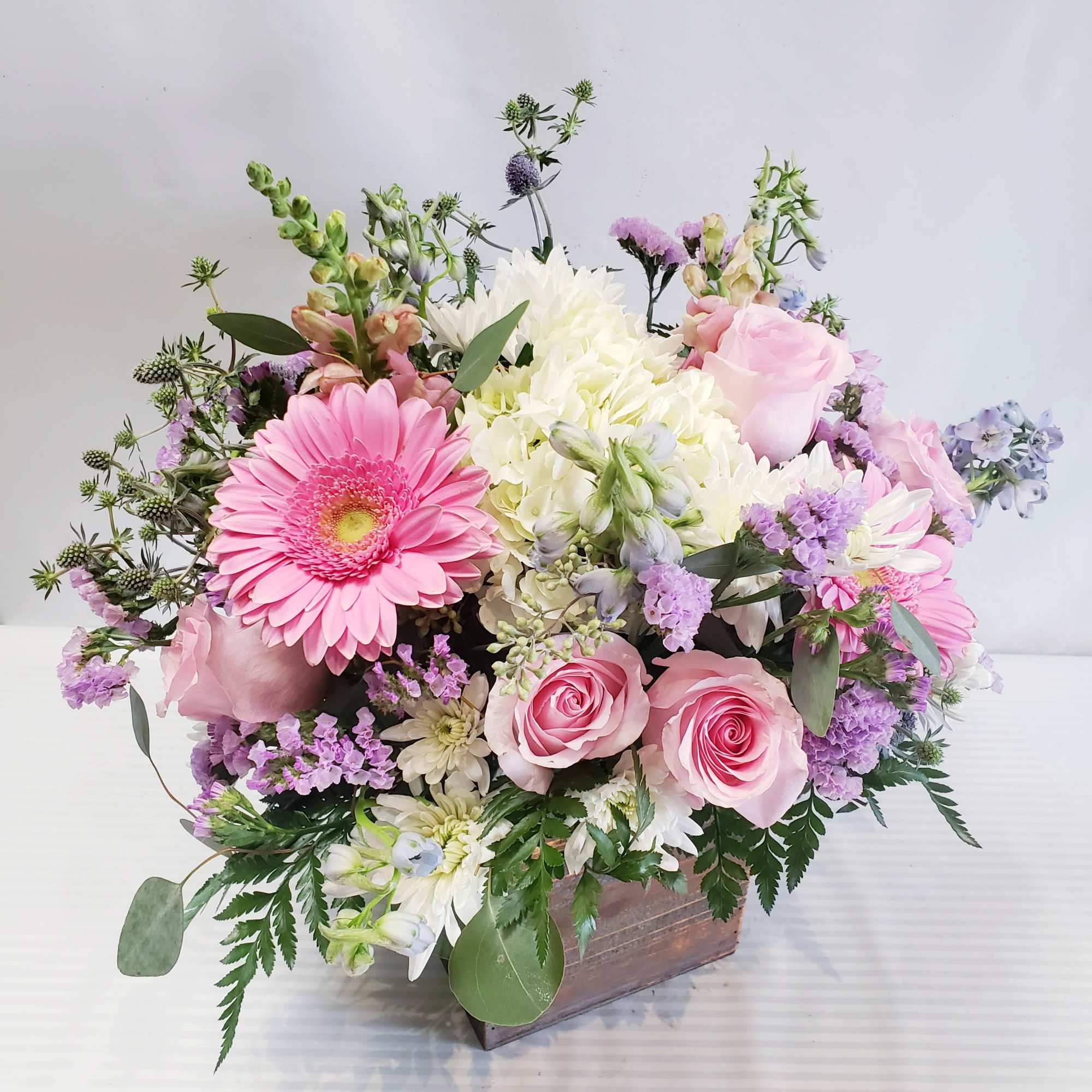 Pink and white mixed flower arrangement in a wooden box