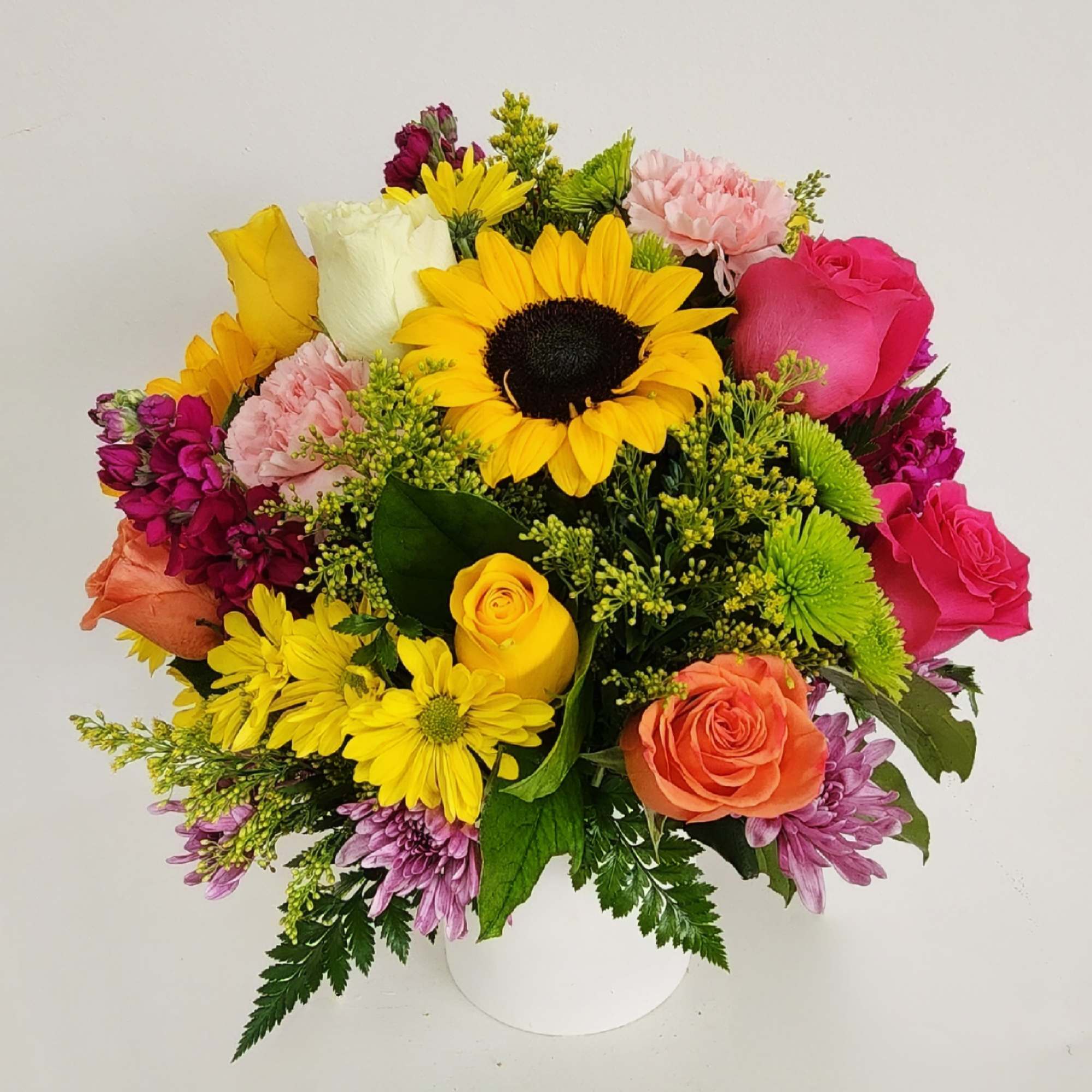 Mixed bouquet with sunflowers, roses, and chrysanthemums in a white vase