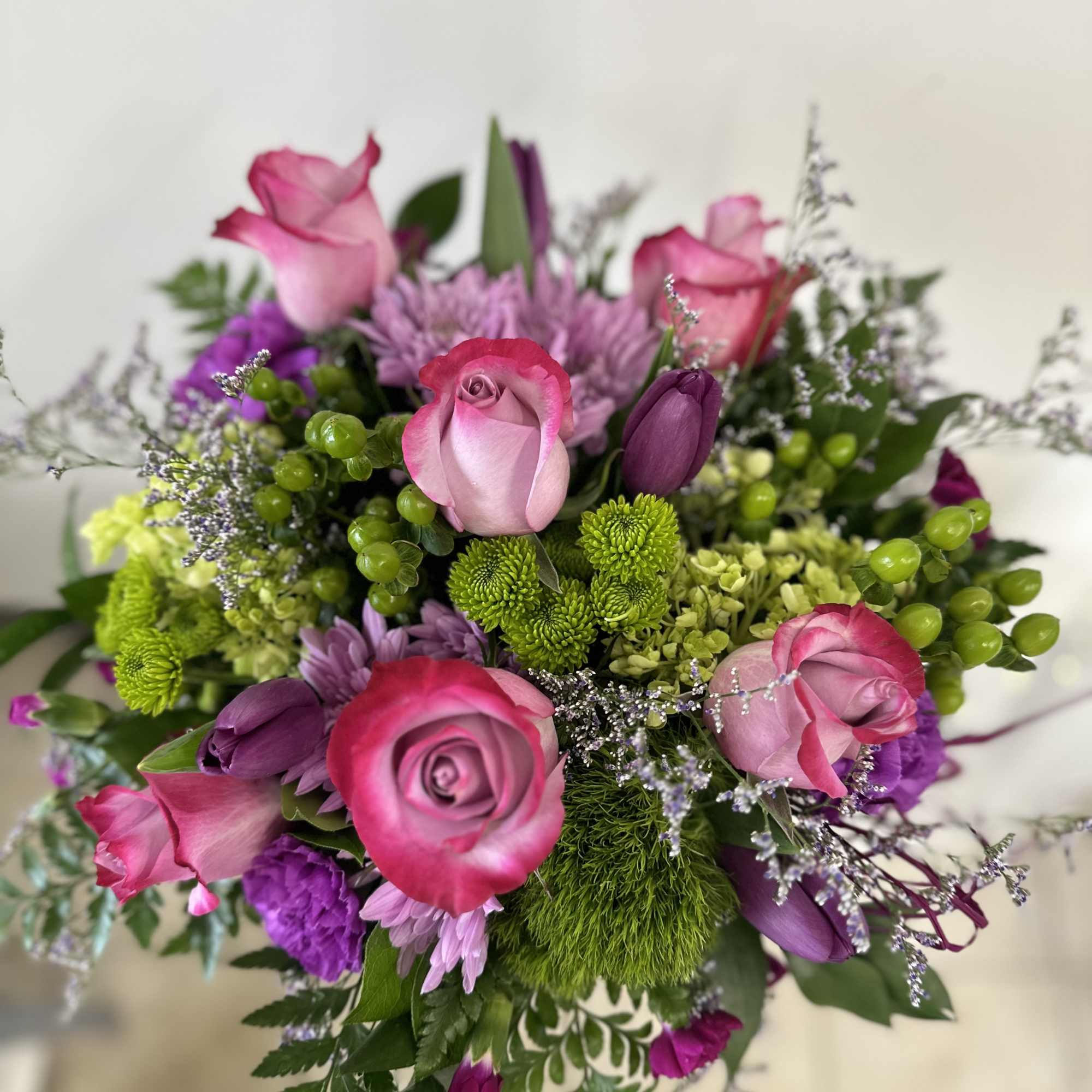 Bouquet of pink roses and purple flowers with green accents
