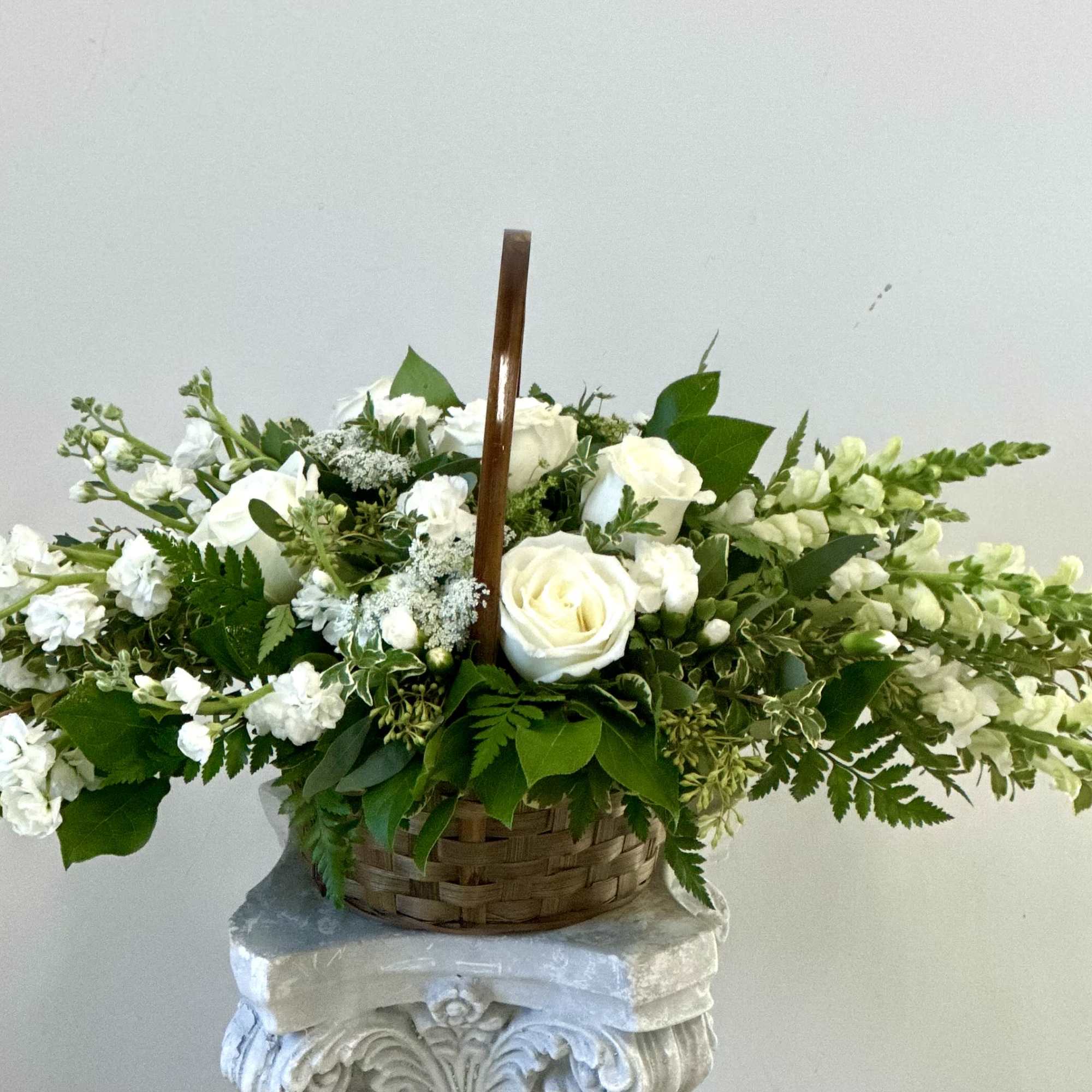 White roses and snapdragons in a woven basket