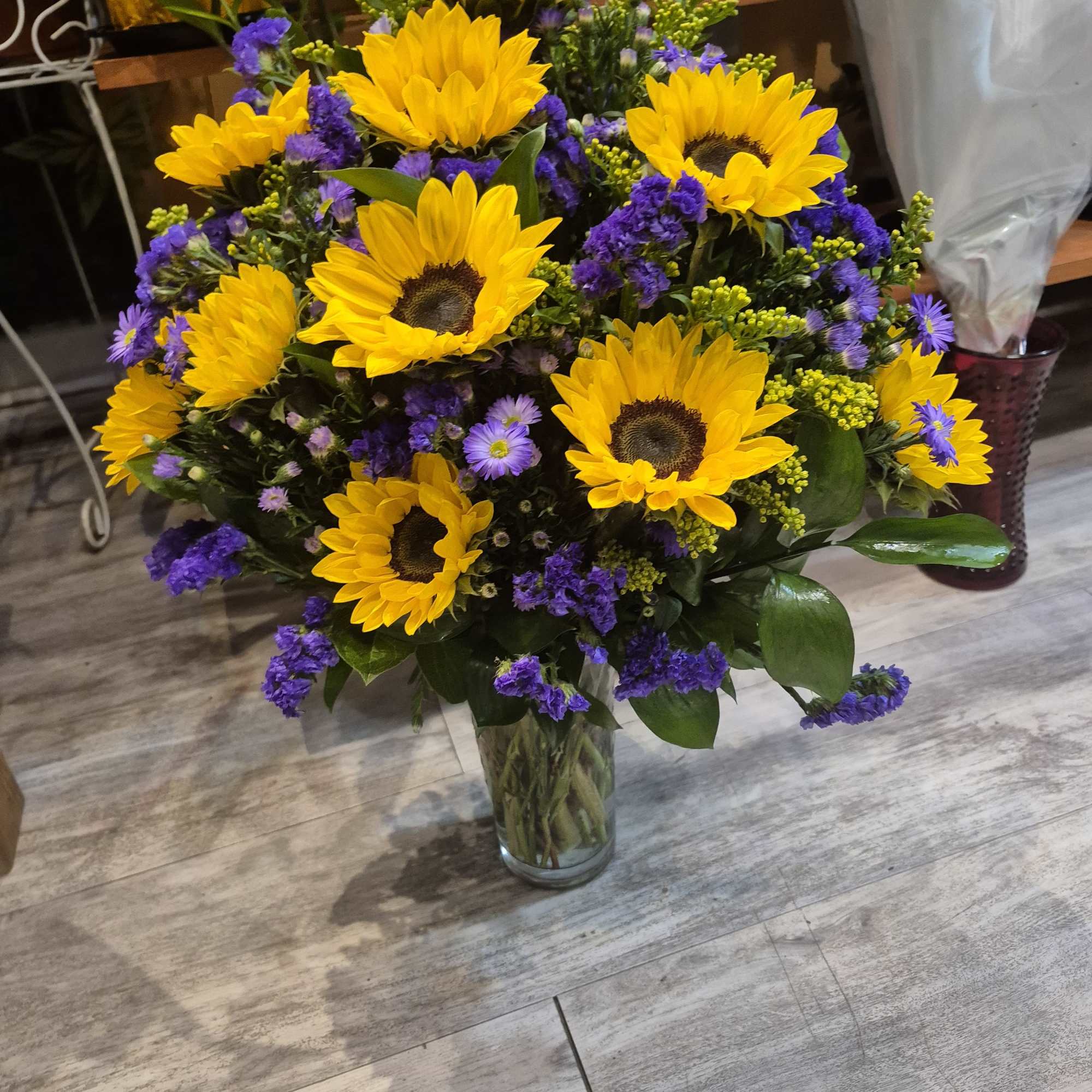 Sunflower bouquet in a clear glass vase with purple filler flowers