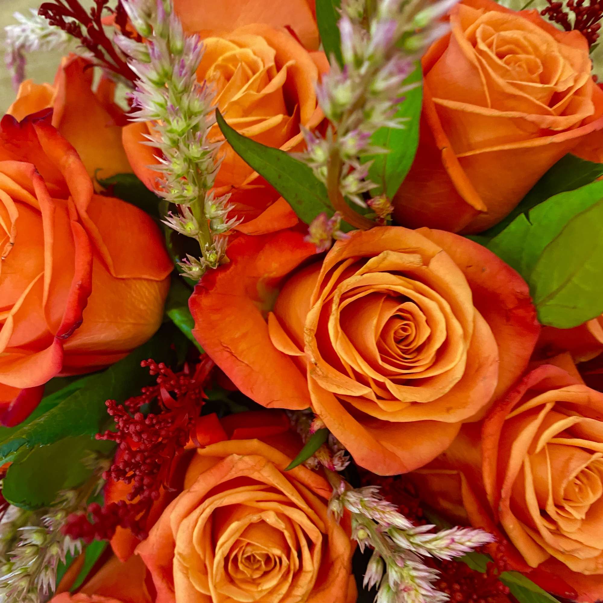 Bouquet of orange roses with red filler flowers