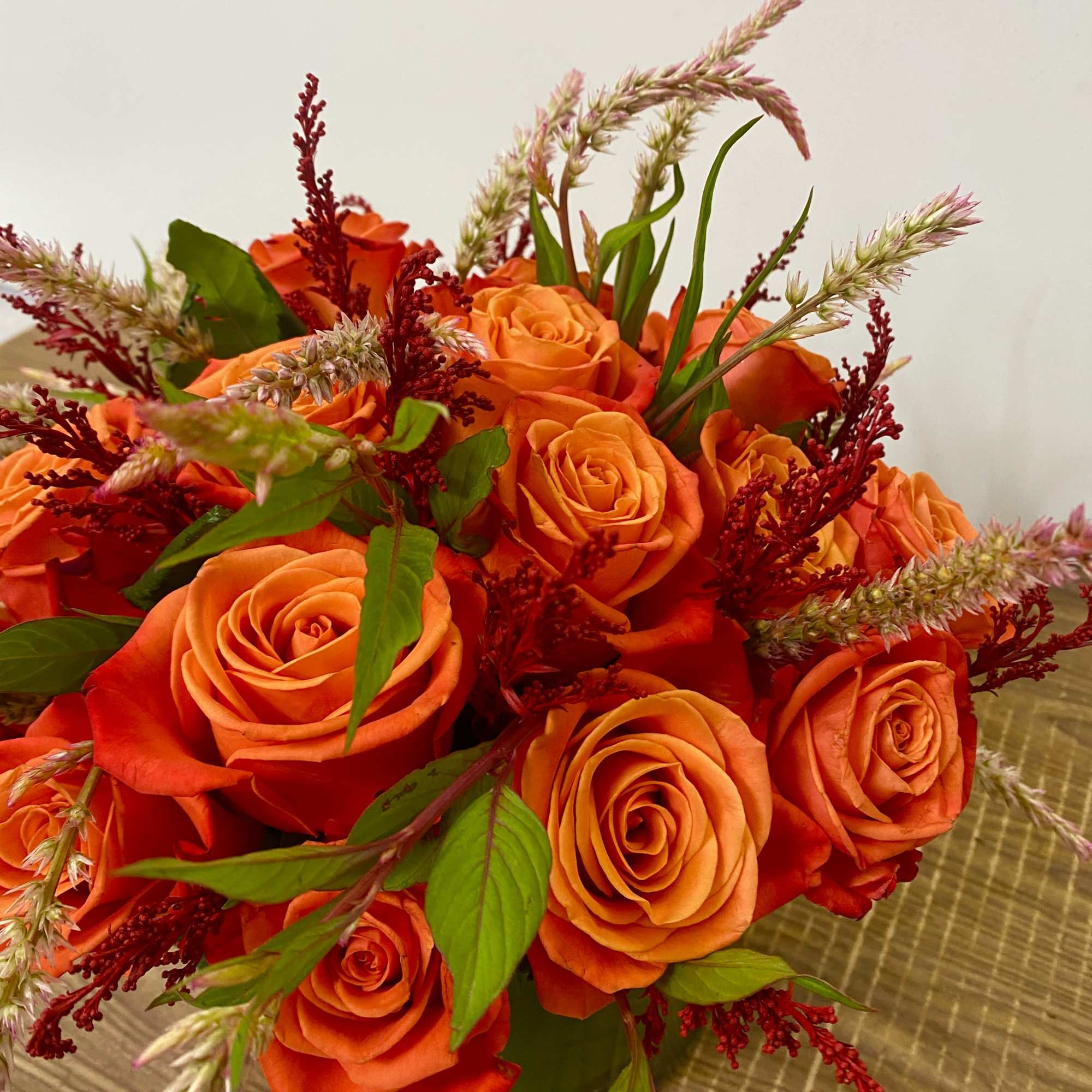 Orange rose bouquet with red accents and green foliage