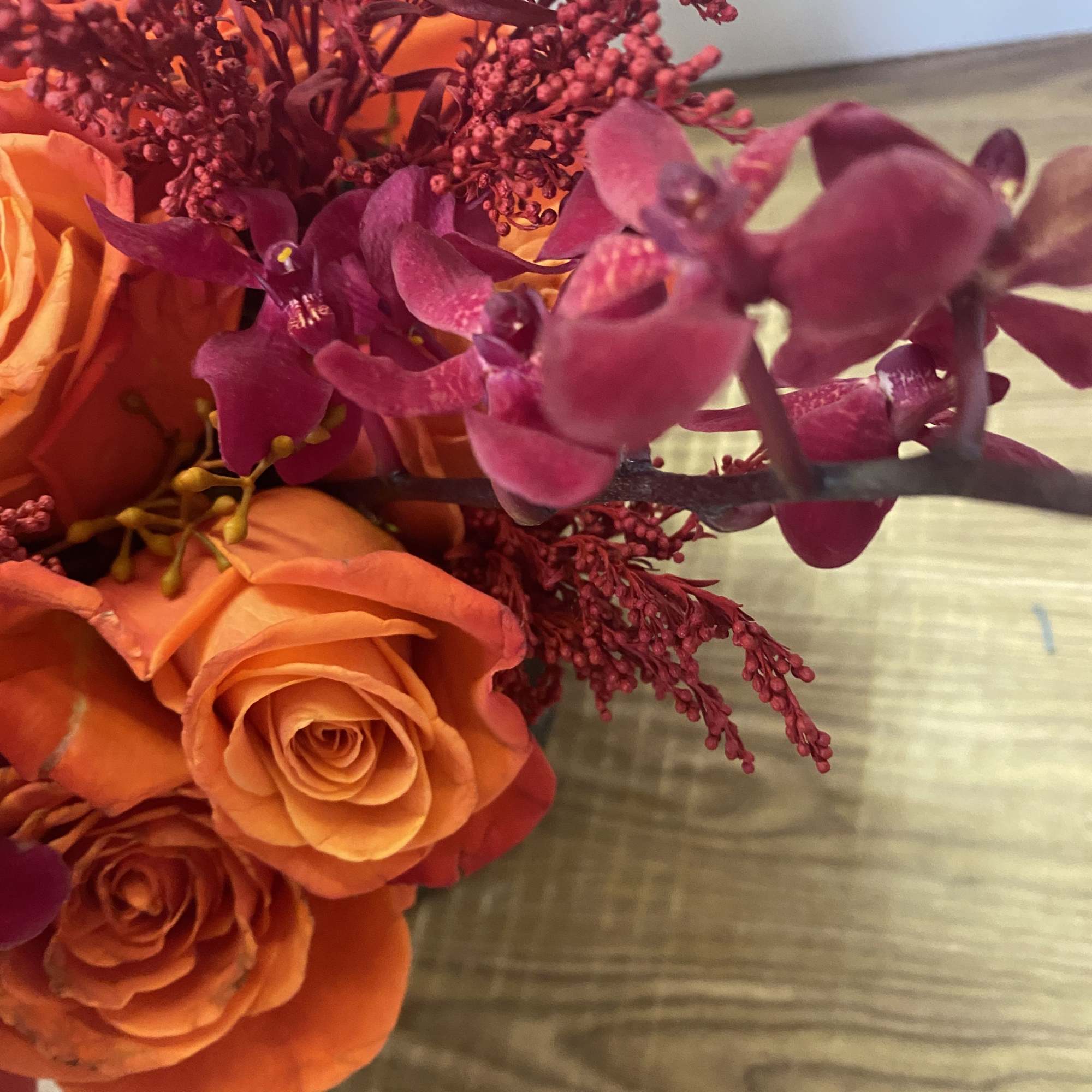 Orange roses with magenta orchids in a bouquet
