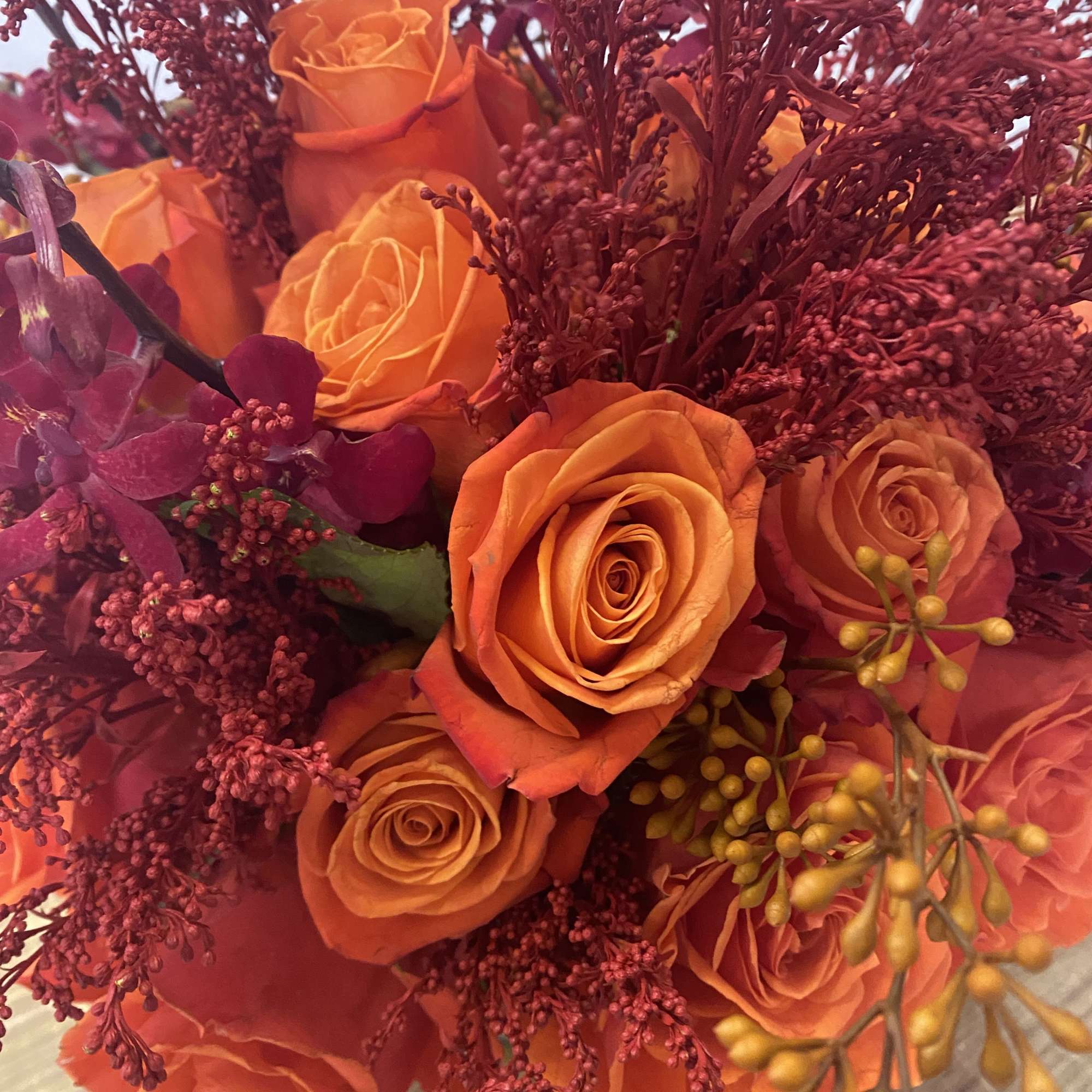 Bouquet of orange roses with burgundy filler flowers