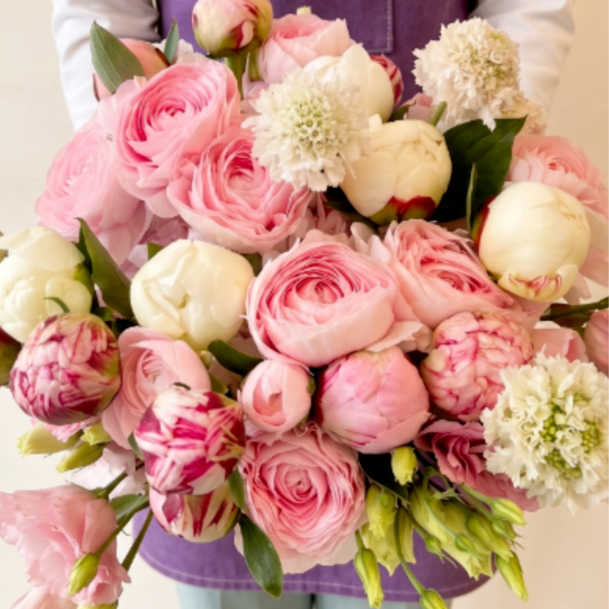 Large bouquet of pink and white flowers held in front of a person