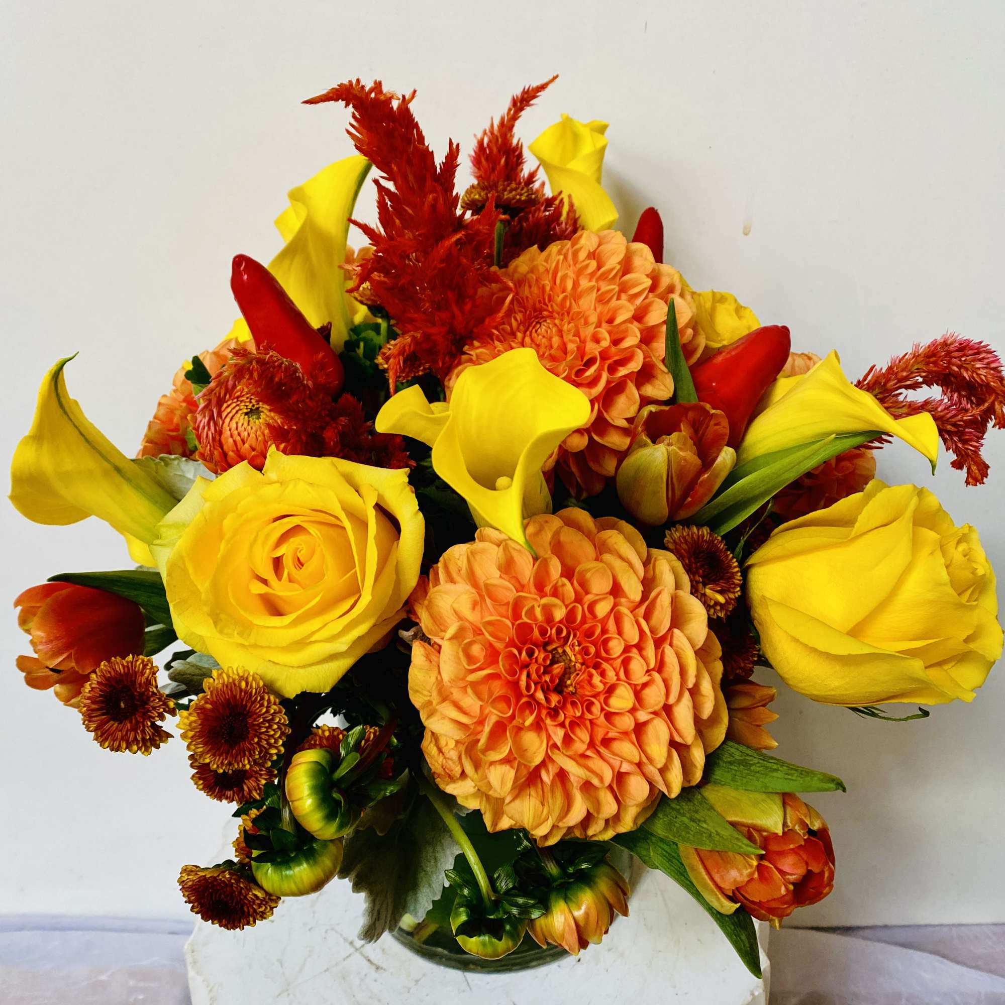 IN A GLASS VASE COMBINATIONS OF YELLOW AND ORANGE FLOWERS