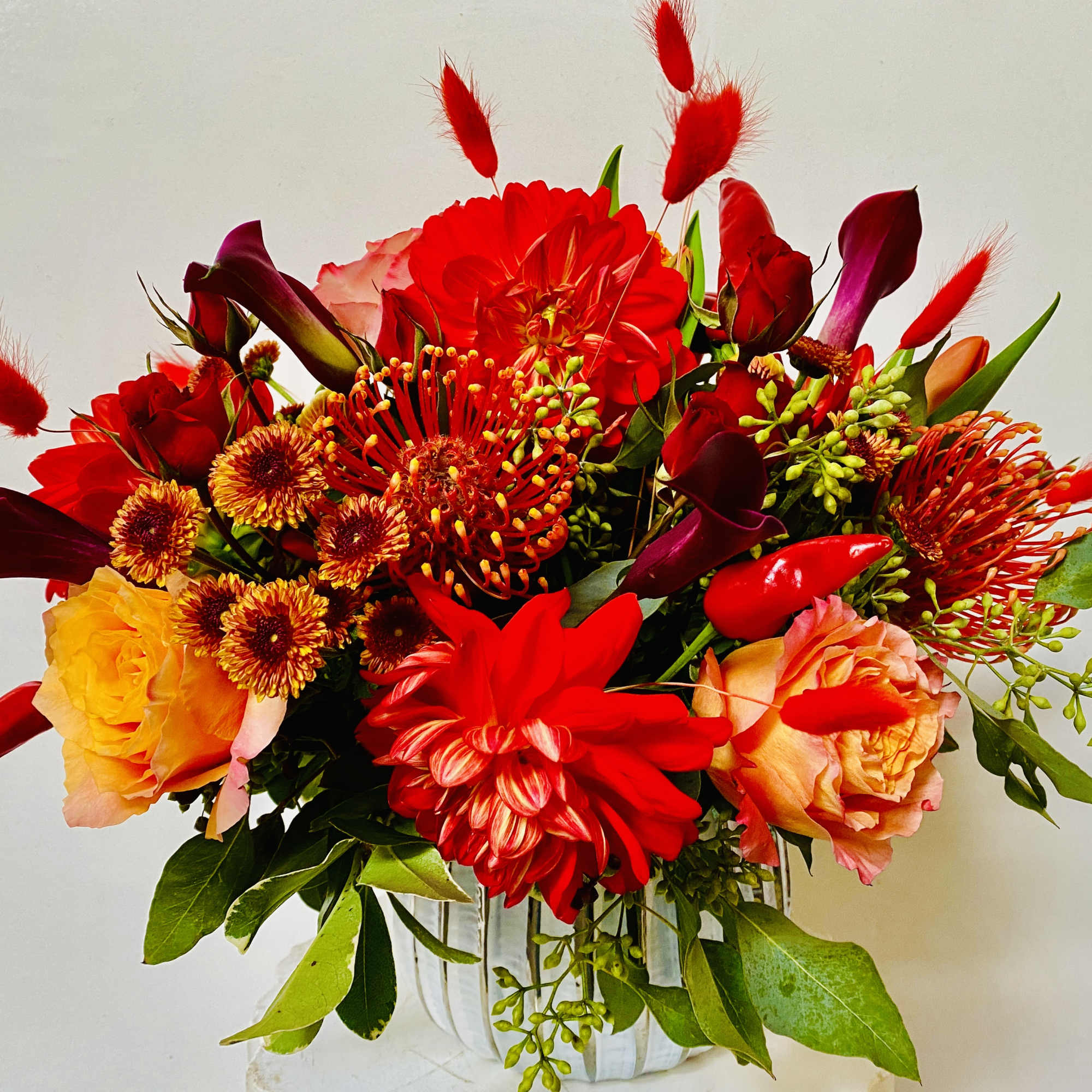 IN A GLASS VASE COMBINATIONS OF YELLOW AND ORANGE FLOWERS
