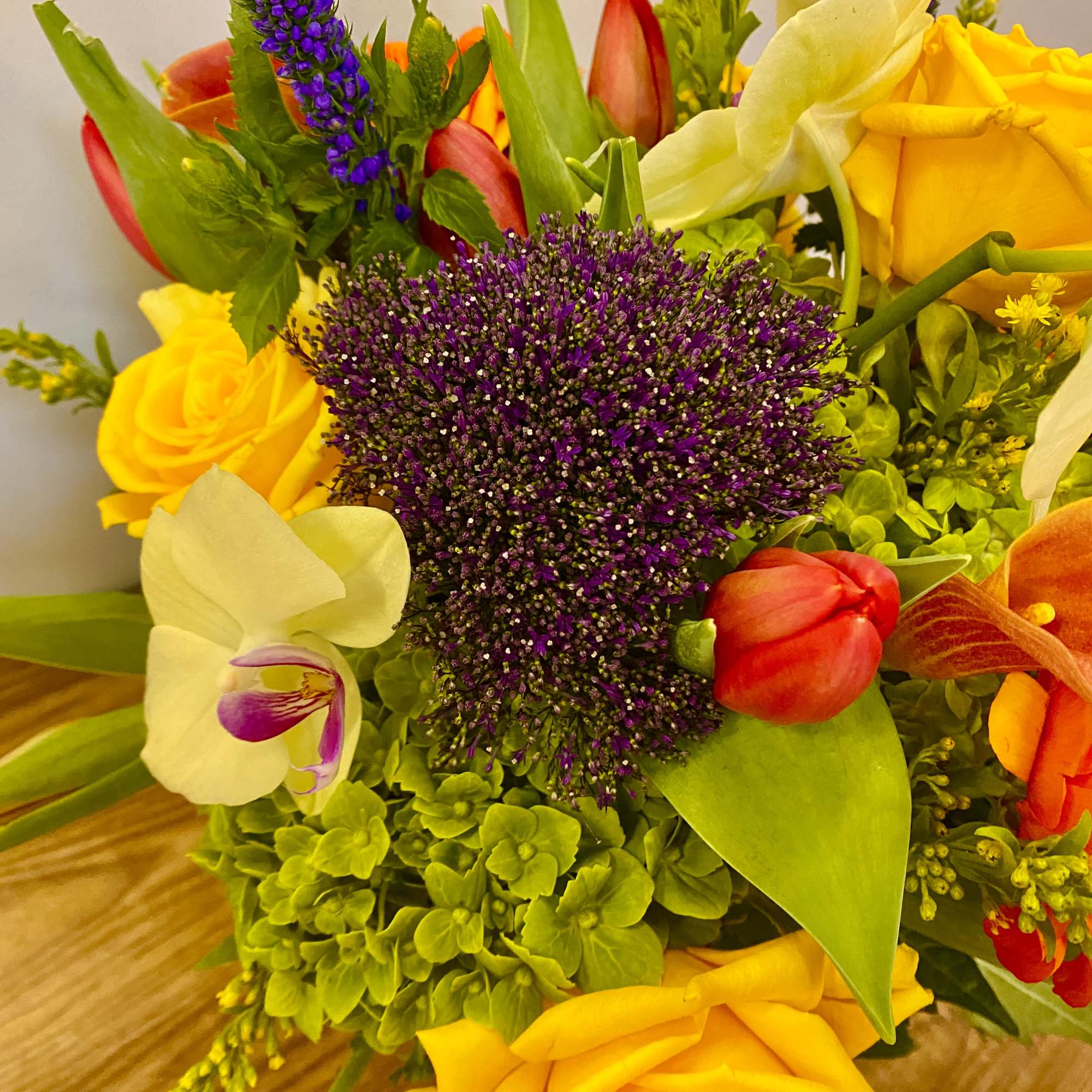 Bright mixed bouquet with yellow roses, red tulips, and purple blooms