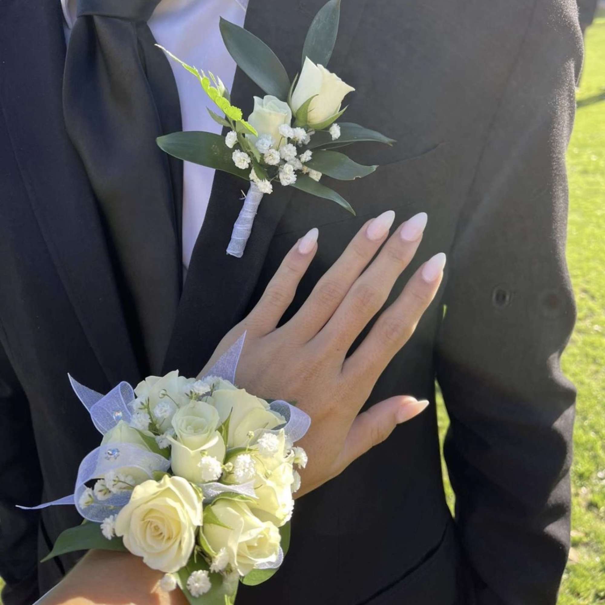 White rose corsage and boutonniere on a black suit