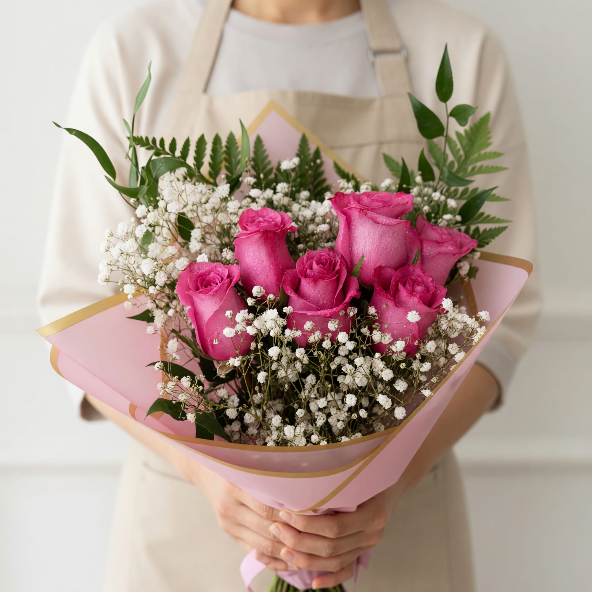 Bright pink roses are clustered at the heart of this hand-tied bouquet