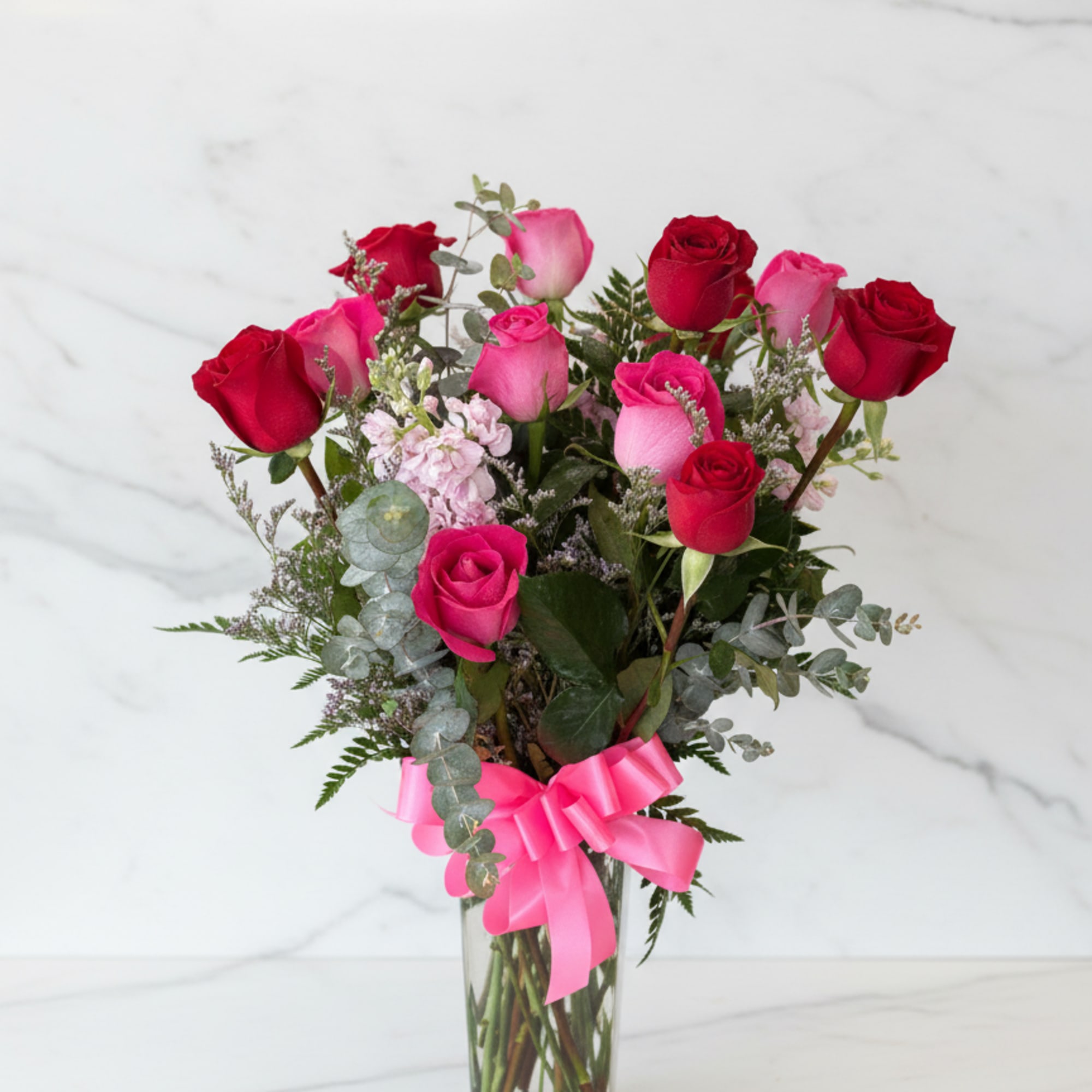 A lush mix of red and pink roses arranged upright in a