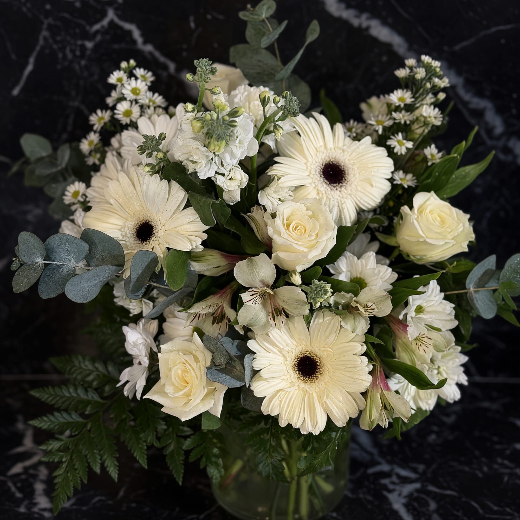 Creamy white gerbera daisies and ivory roses form the heart of this