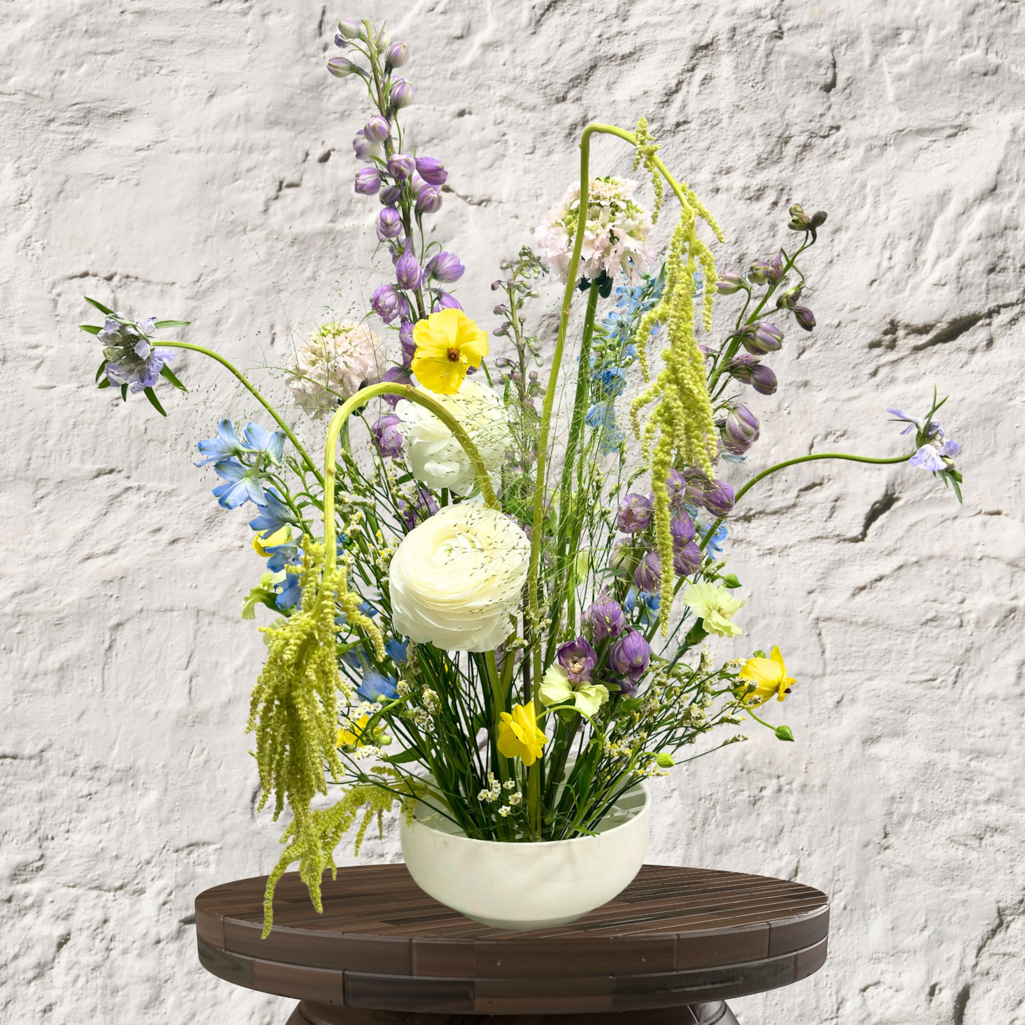 Tall mixed flower arrangement in a white bowl vase