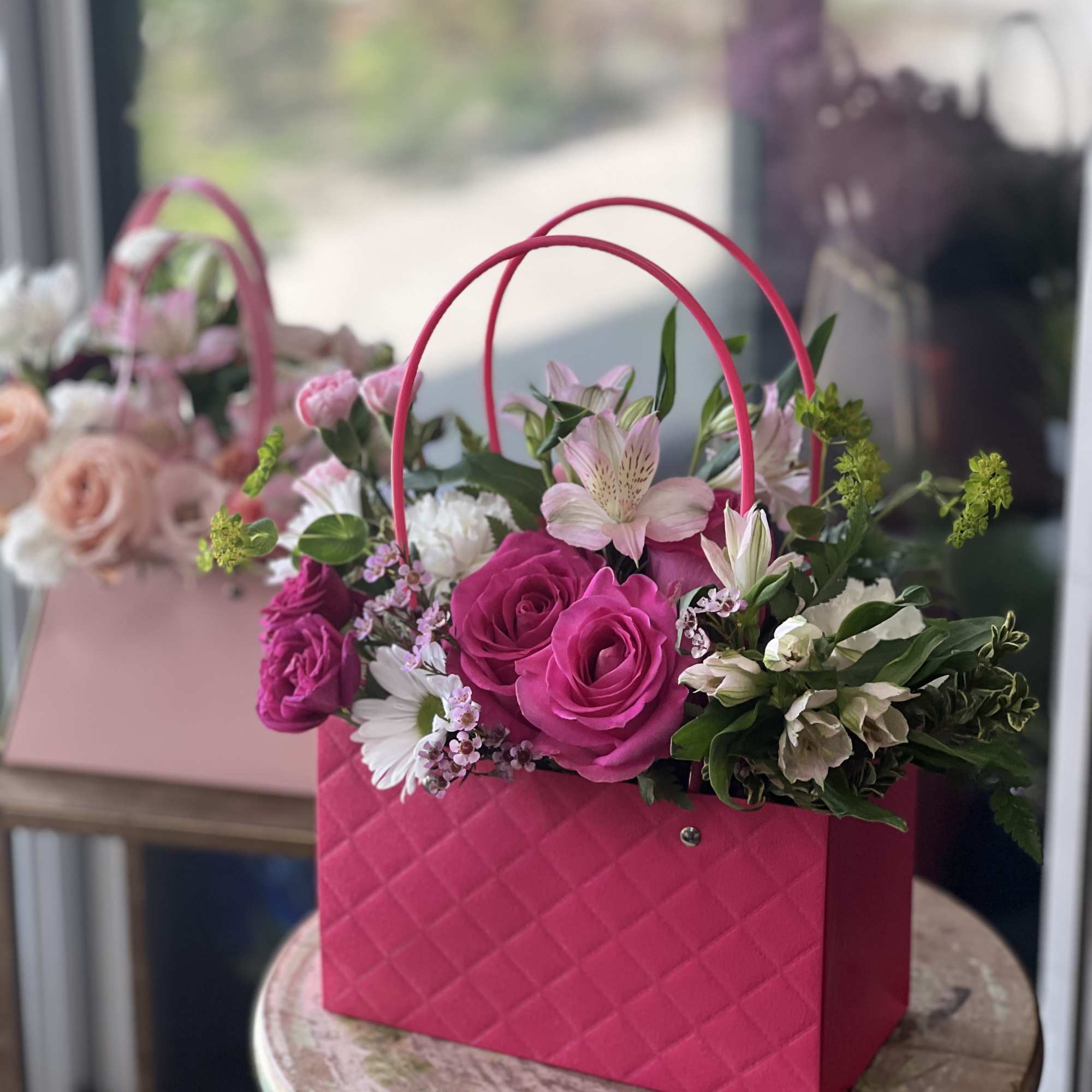 Pink handbag-style flower arrangement with roses and lilies