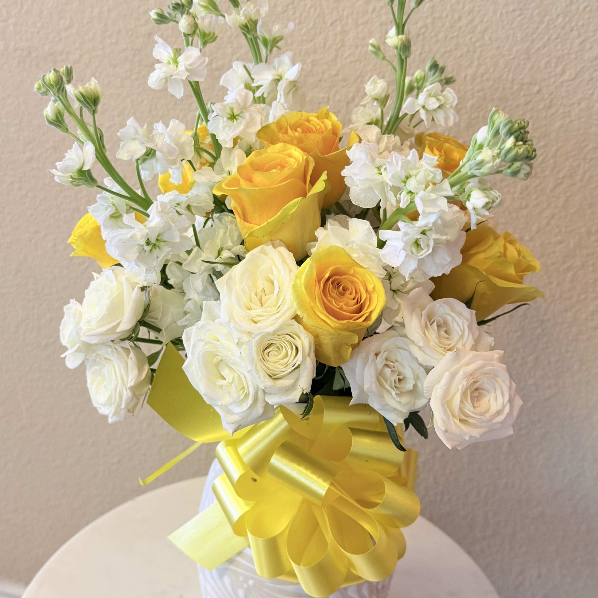 Sunlit yellow roses mingle with soft white roses and tall white stock