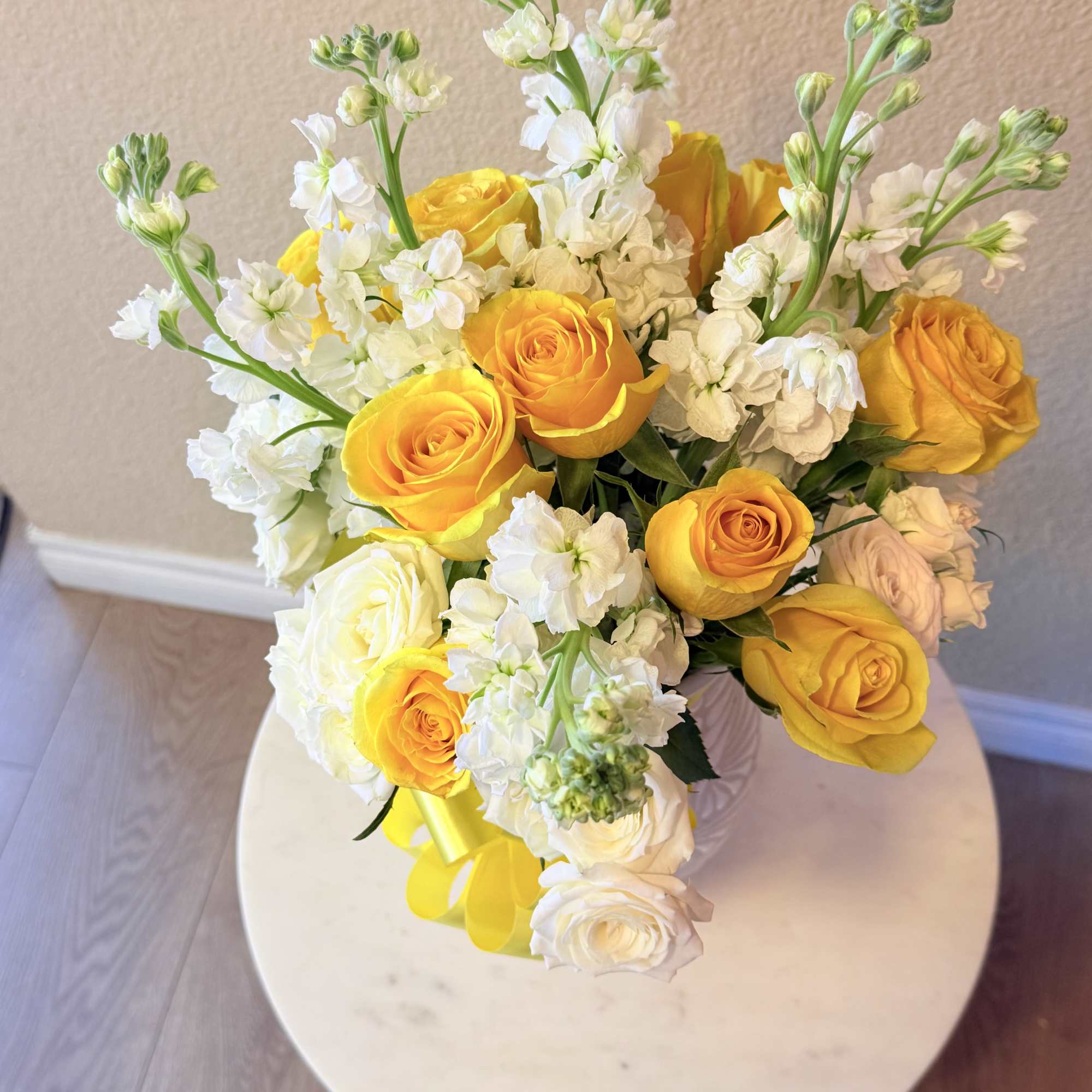 Sunlit yellow roses mingle with soft white roses and tall white stock