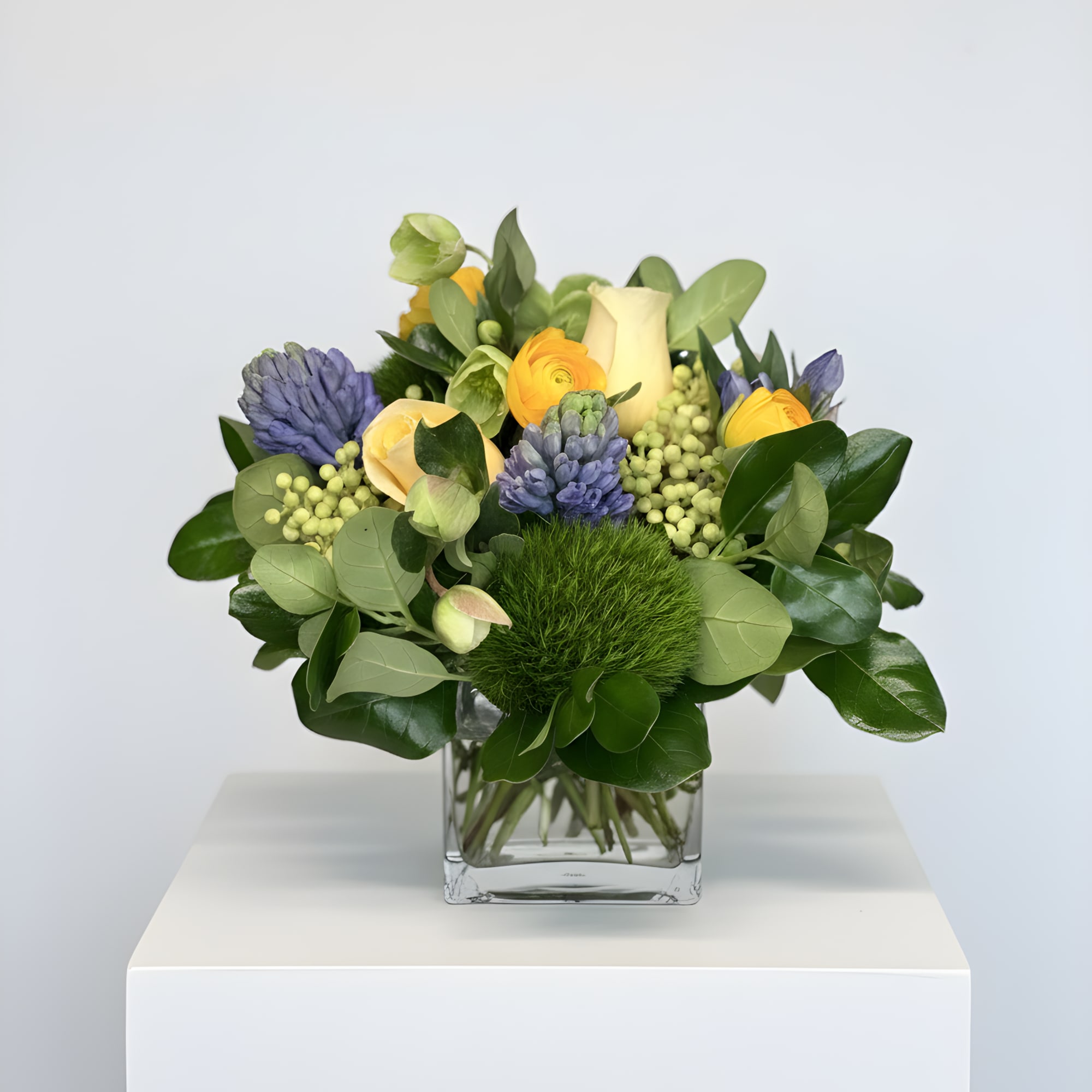 Happy blue and yellow spring blooms: ranunculus, hyacinths, roses and a pop