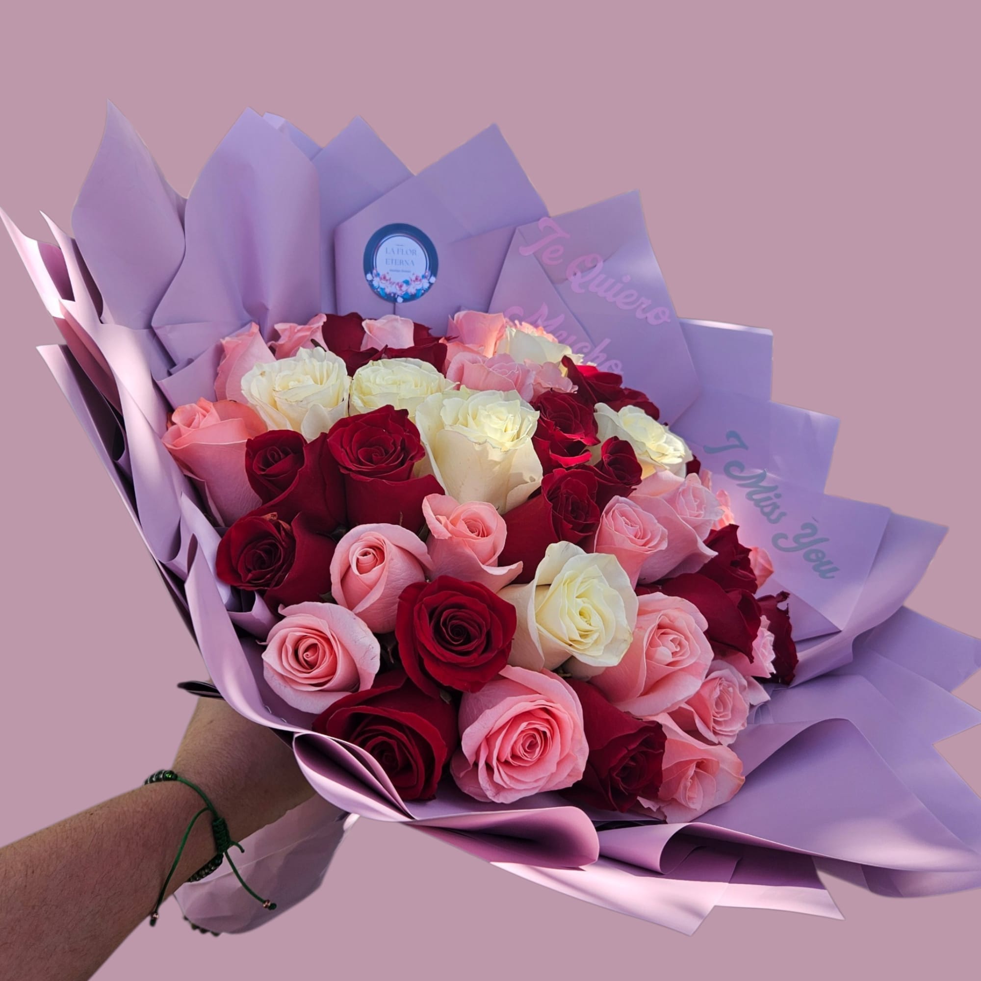 A lush hand-tied bouquet of roses in deep red, blush pink, creamy