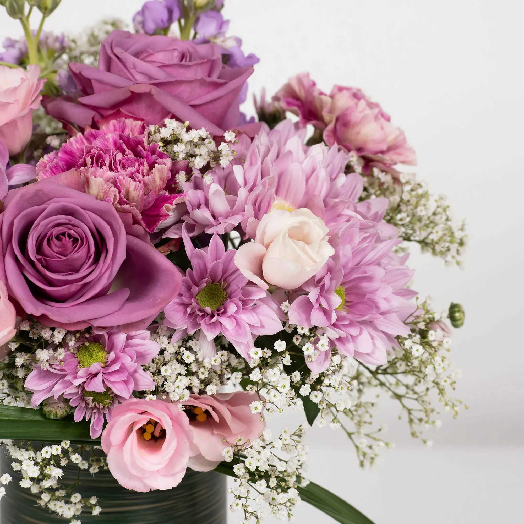 Pink and purple bouquet with roses, daisies, and small white filler flowers in a vase