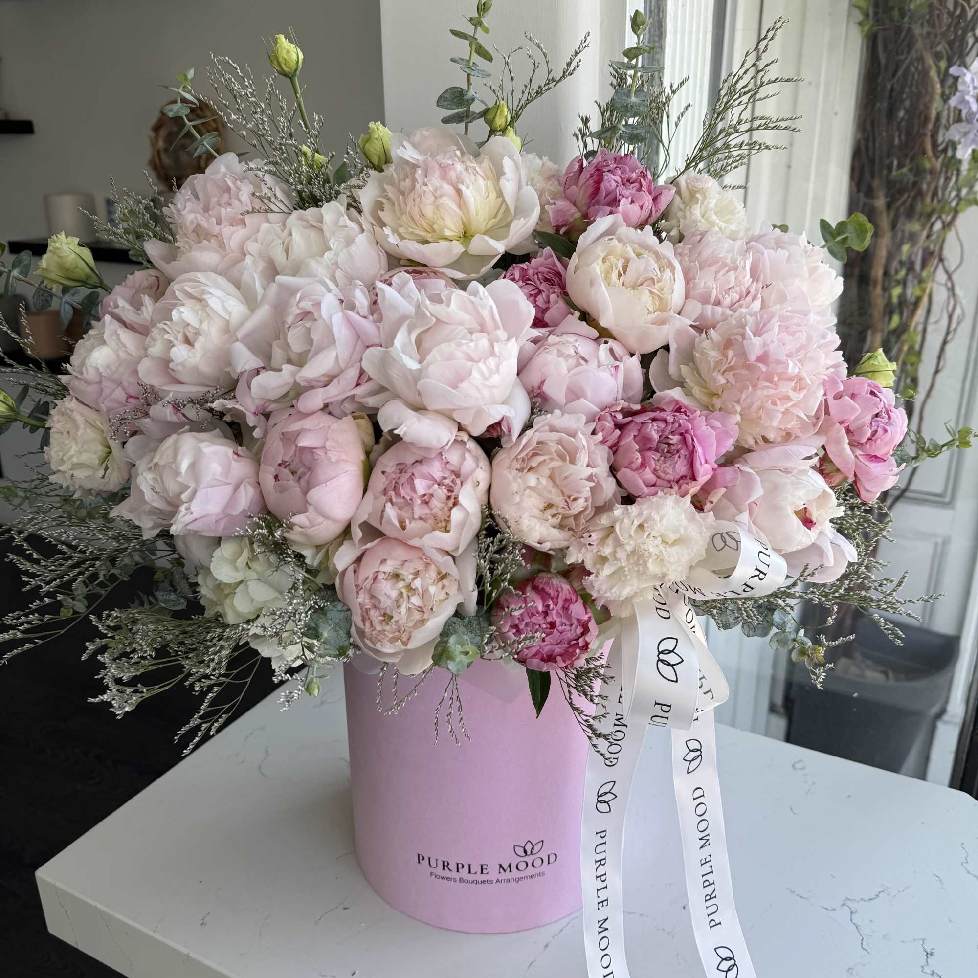Pink and white peony bouquet in a pink hatbox with ribbon
