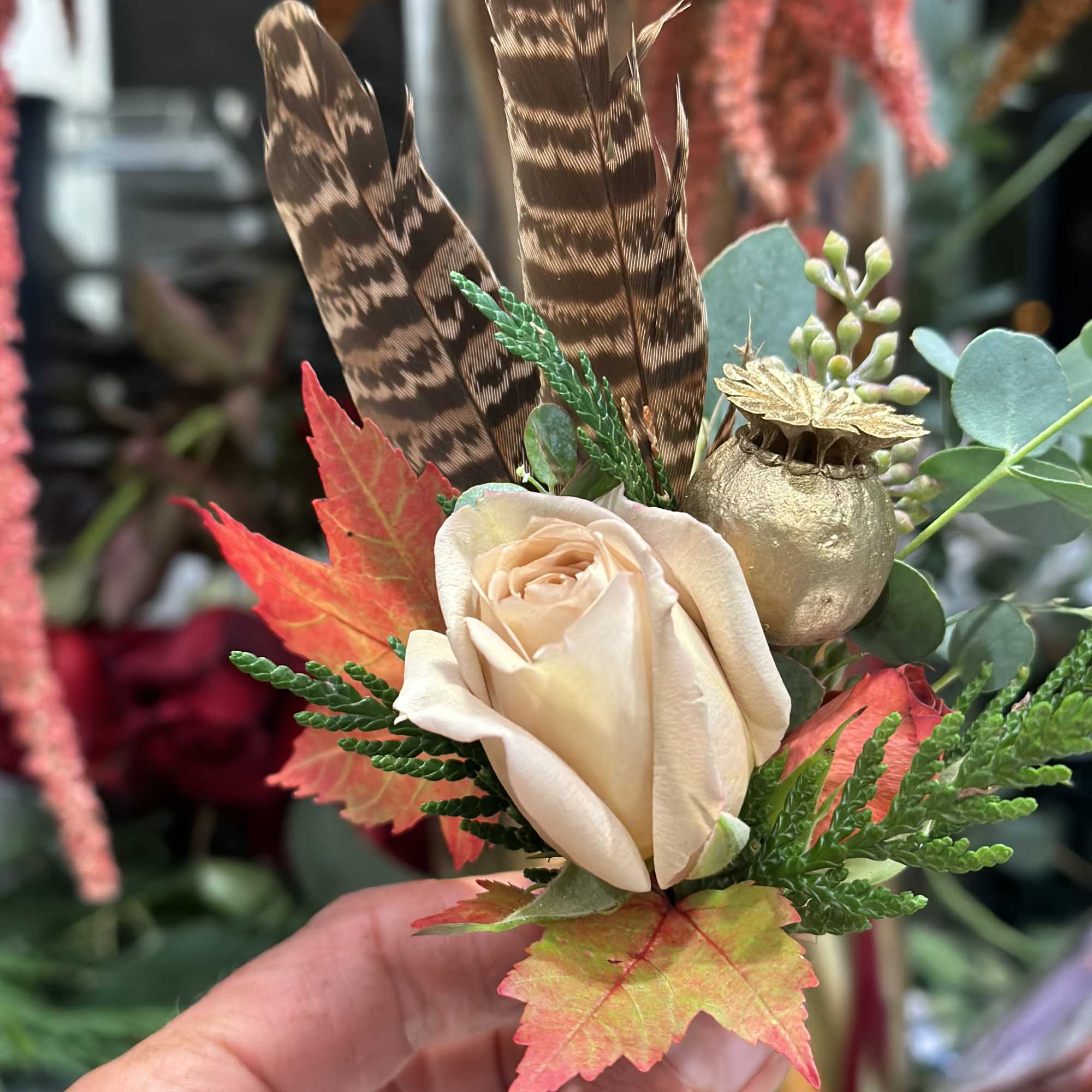 Cream rose with feathers, autumn leaves, and a gold pod accent