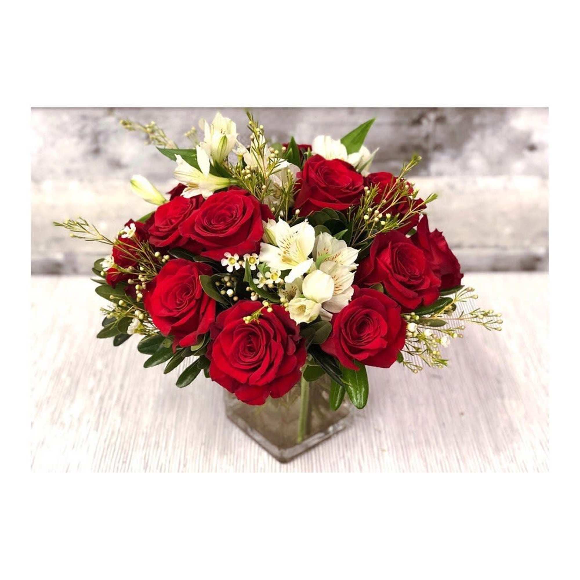Red roses and white flowers arranged in a clear square vase