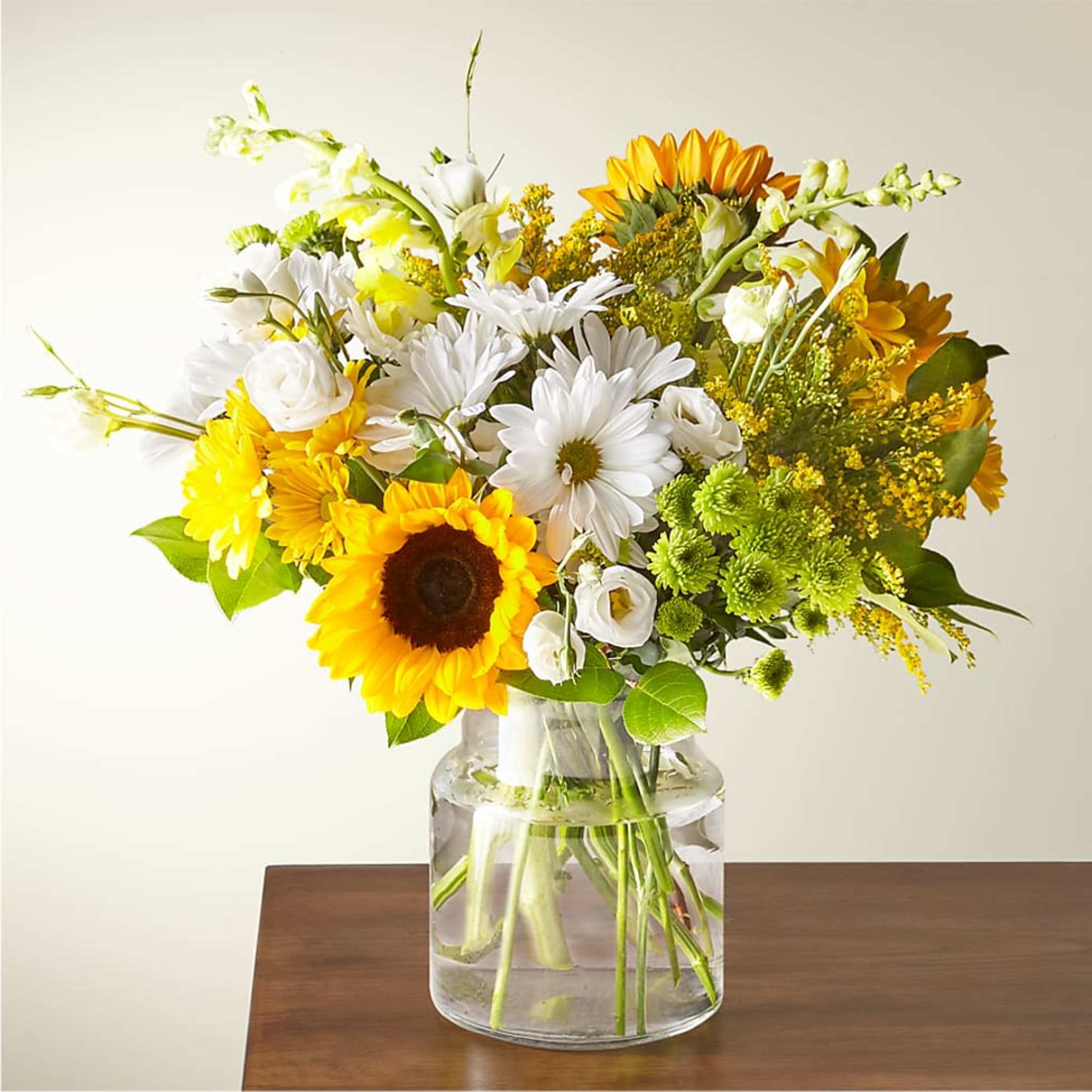 Bouquet of sunflowers, white daisies, and yellow flowers in a glass vase