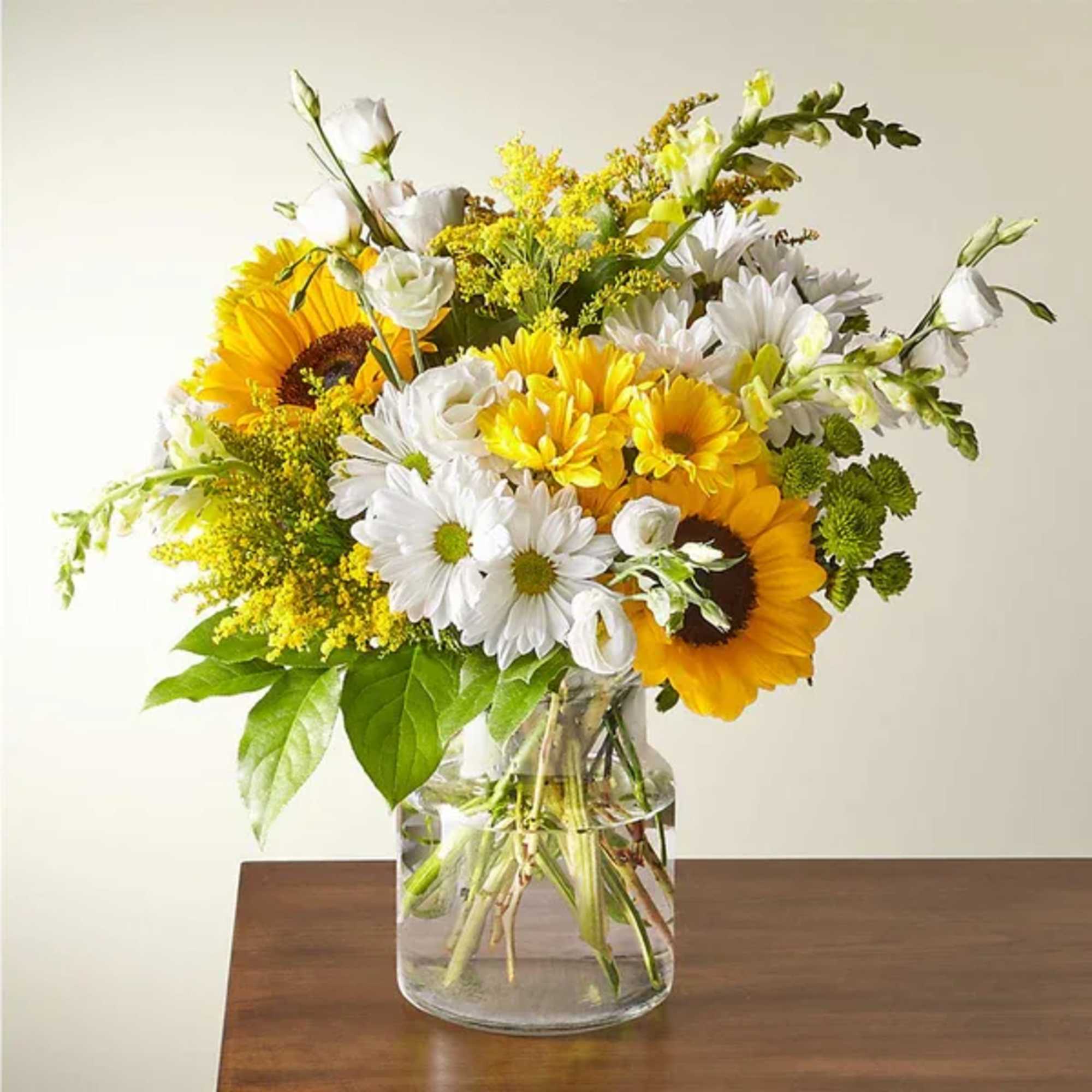 Bouquet of sunflowers, white daisies, and yellow filler in a glass vase
