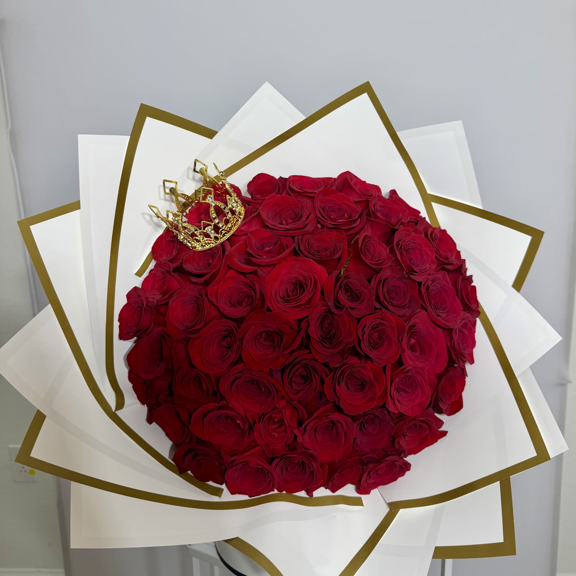 Classic red roses wrapped in white paper with elegant gold details, finished