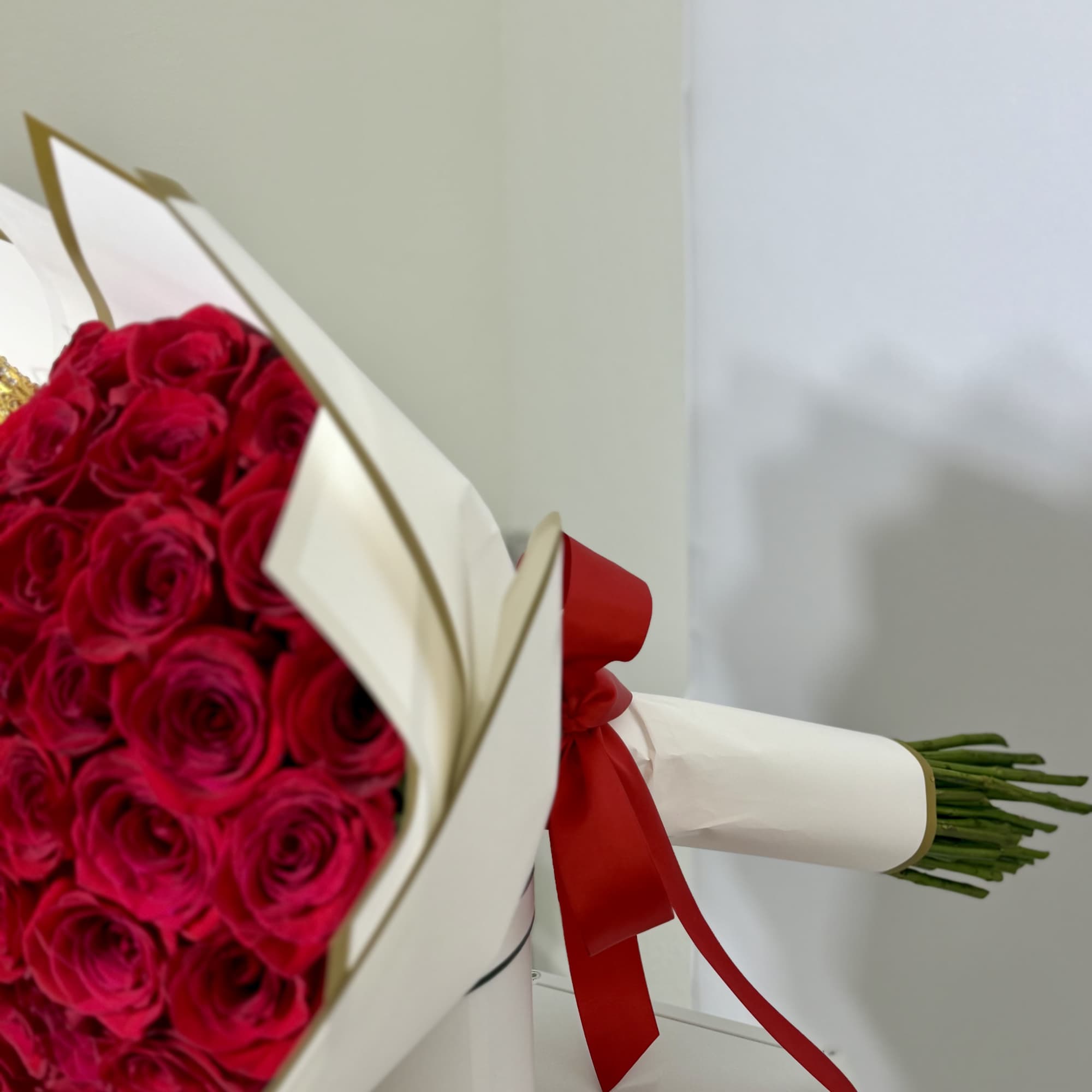 Classic red roses wrapped in white paper with elegant gold details, finished