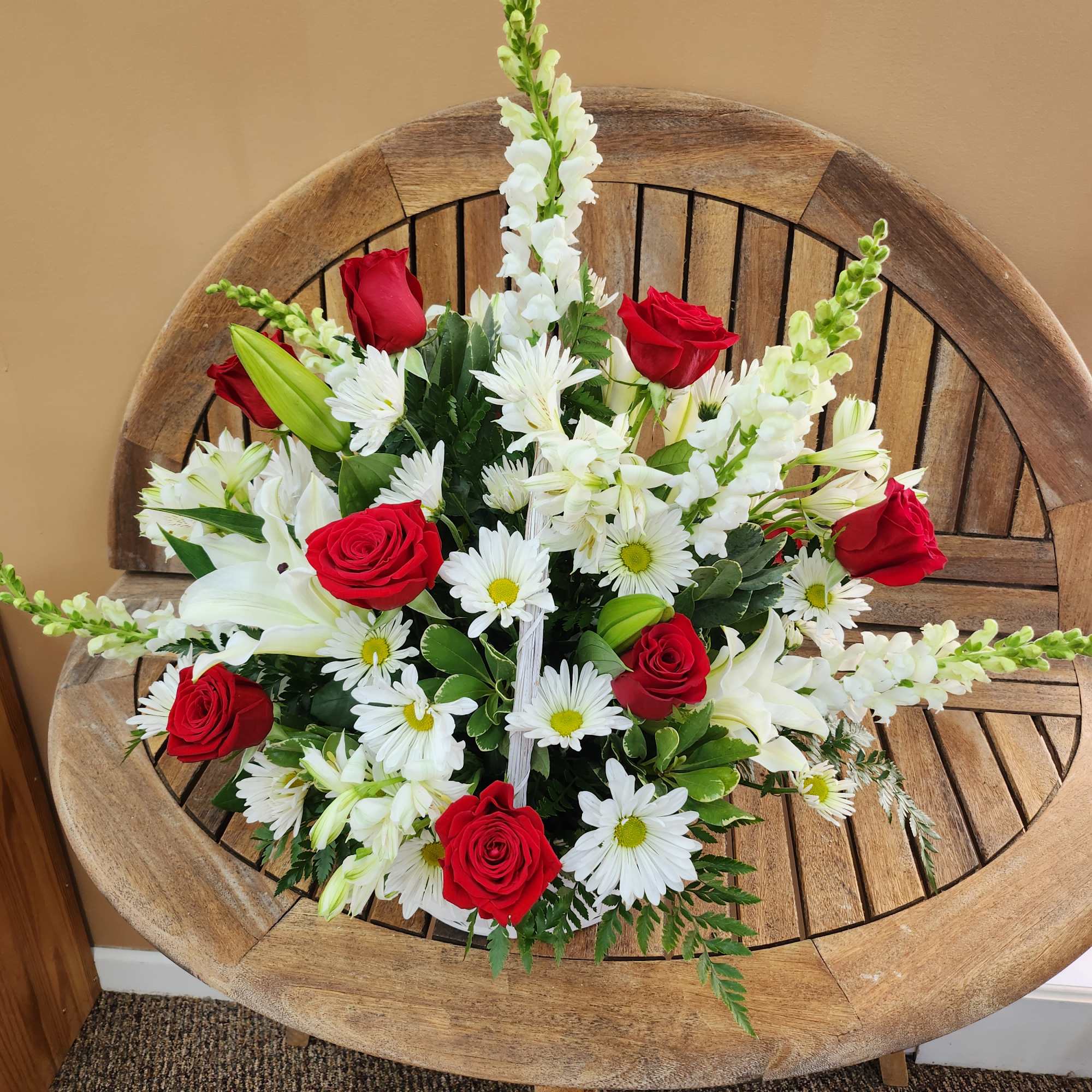Red roses and white daisies arranged in a wooden chair