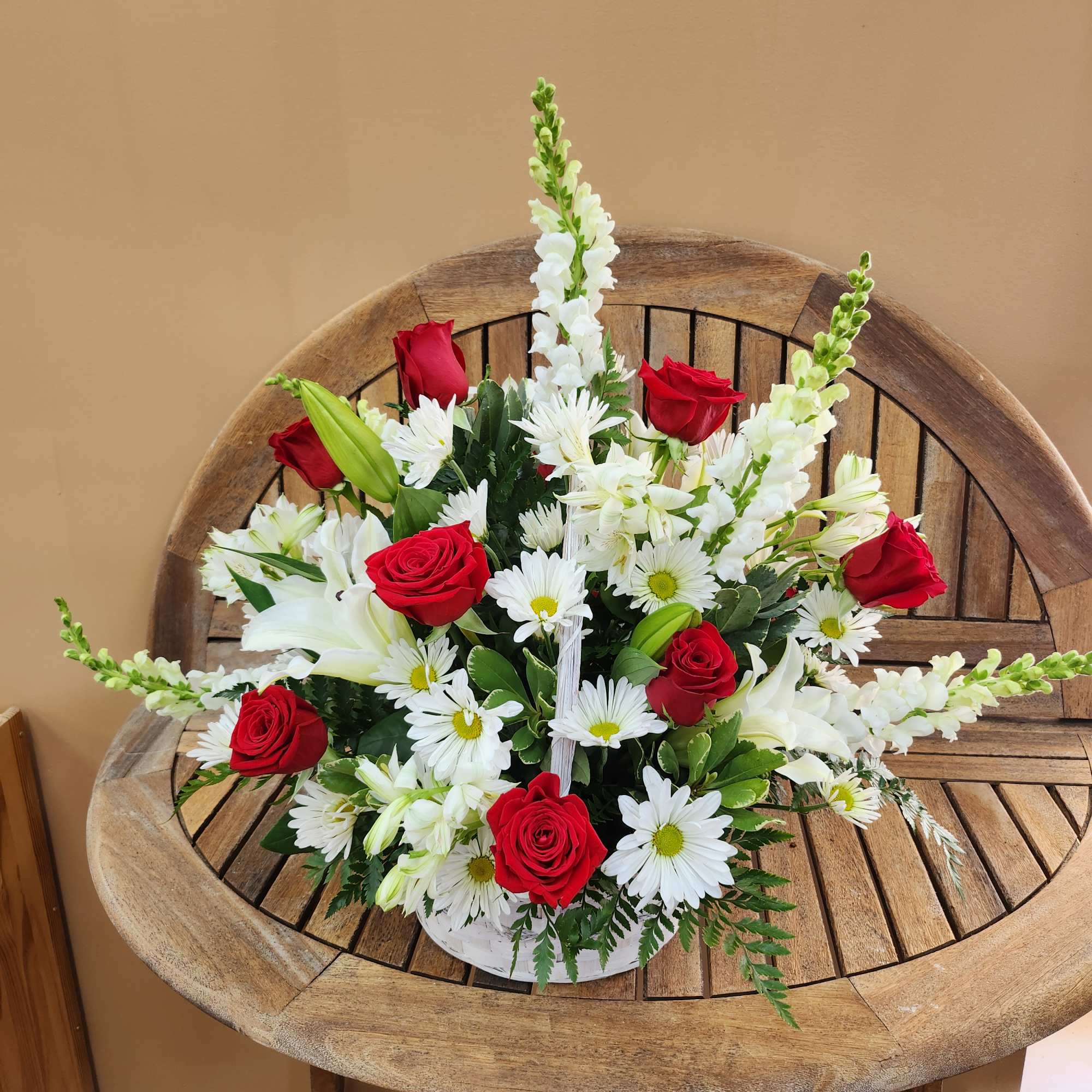 Red roses and white daisies arranged in a white basket