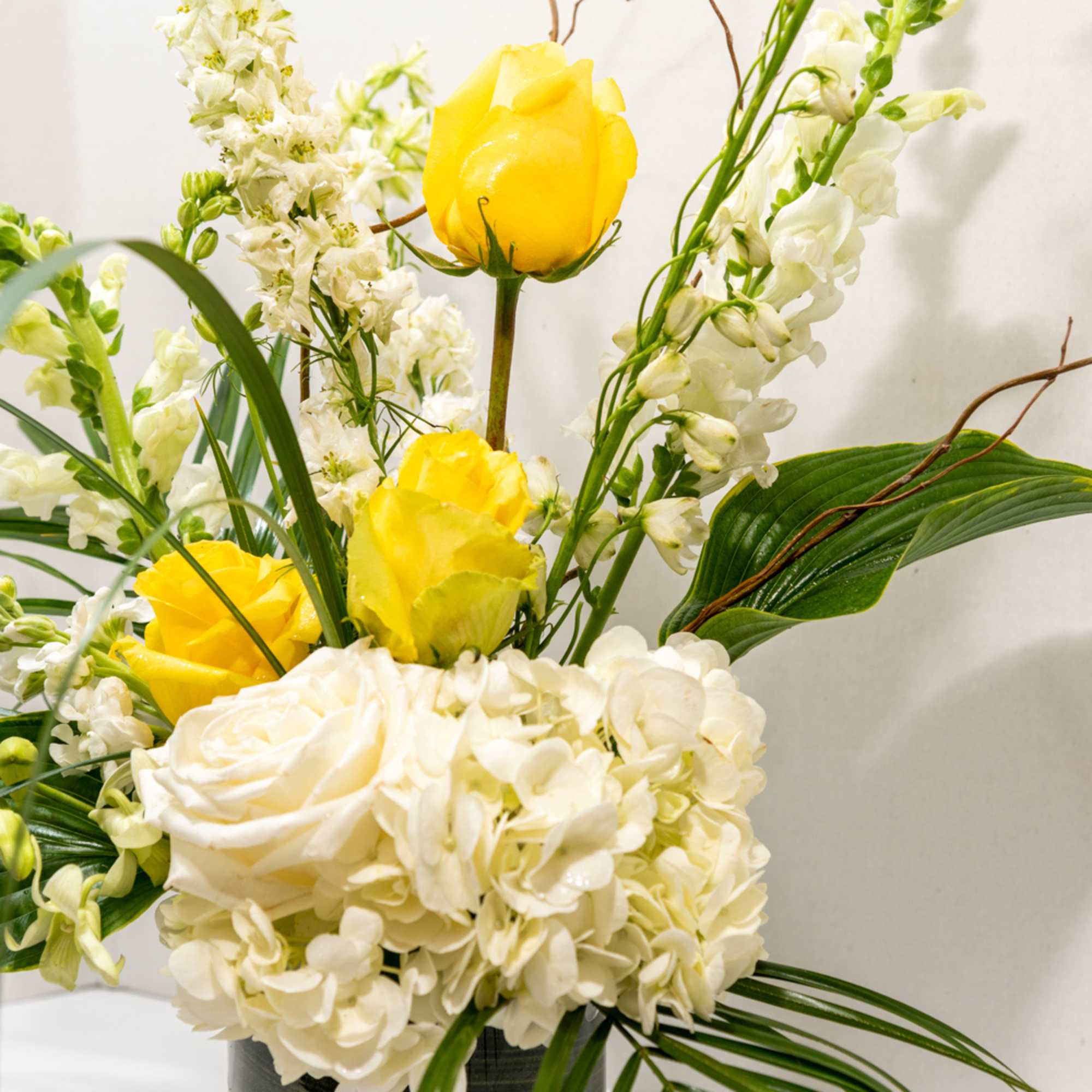 Yellow roses and white flowers arranged in a vase