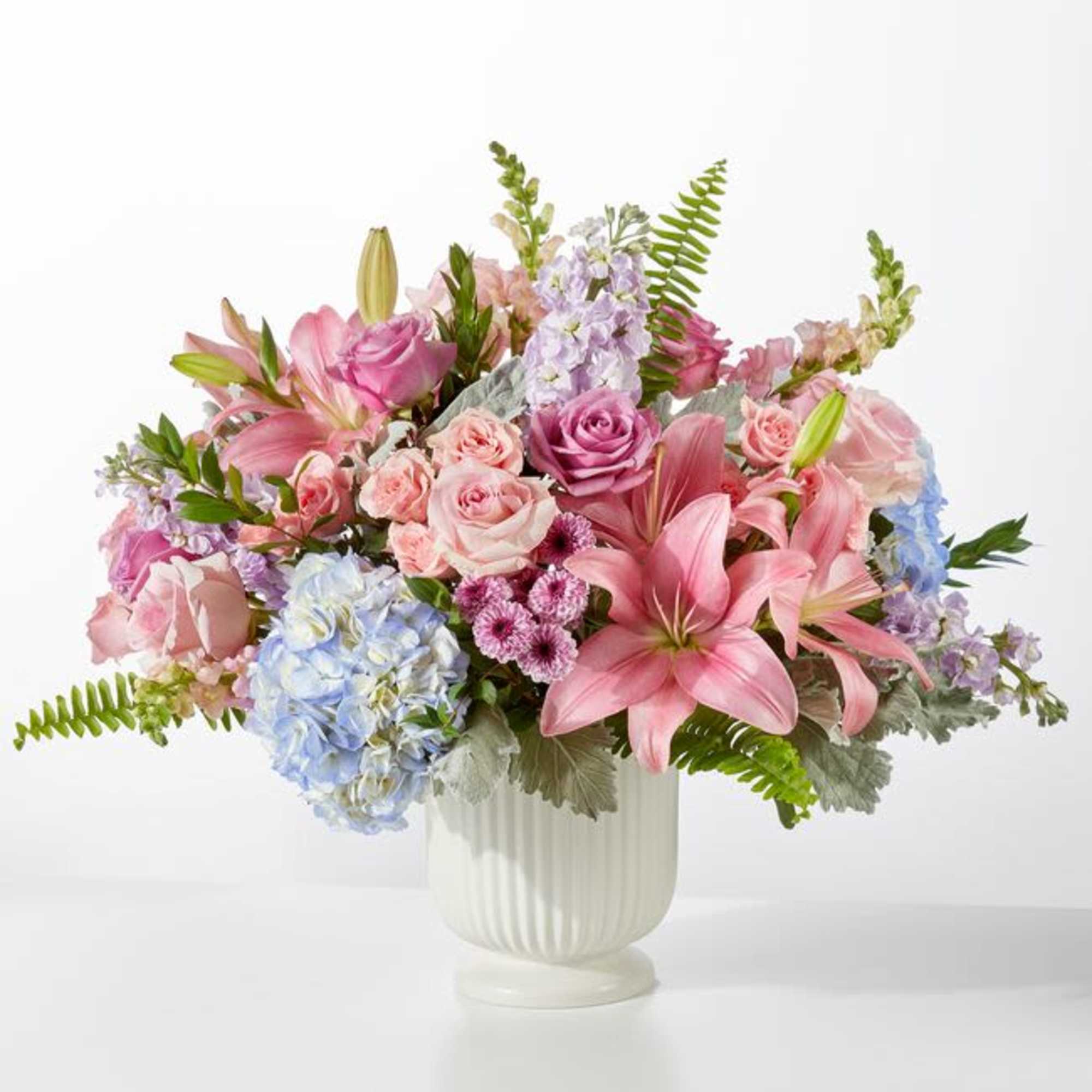 Soft pastel pink lilies and roses mingle with pale blue hydrangeas and