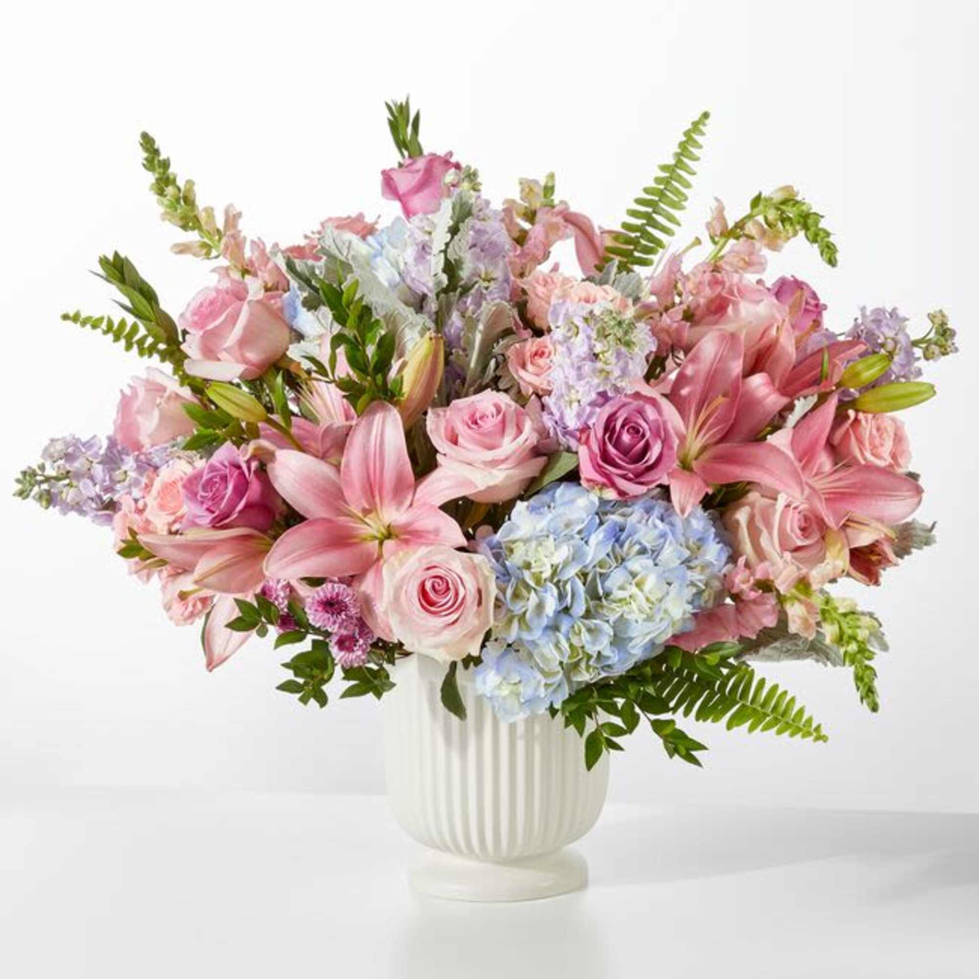 Soft pastel pink lilies and roses mingle with pale blue hydrangeas and