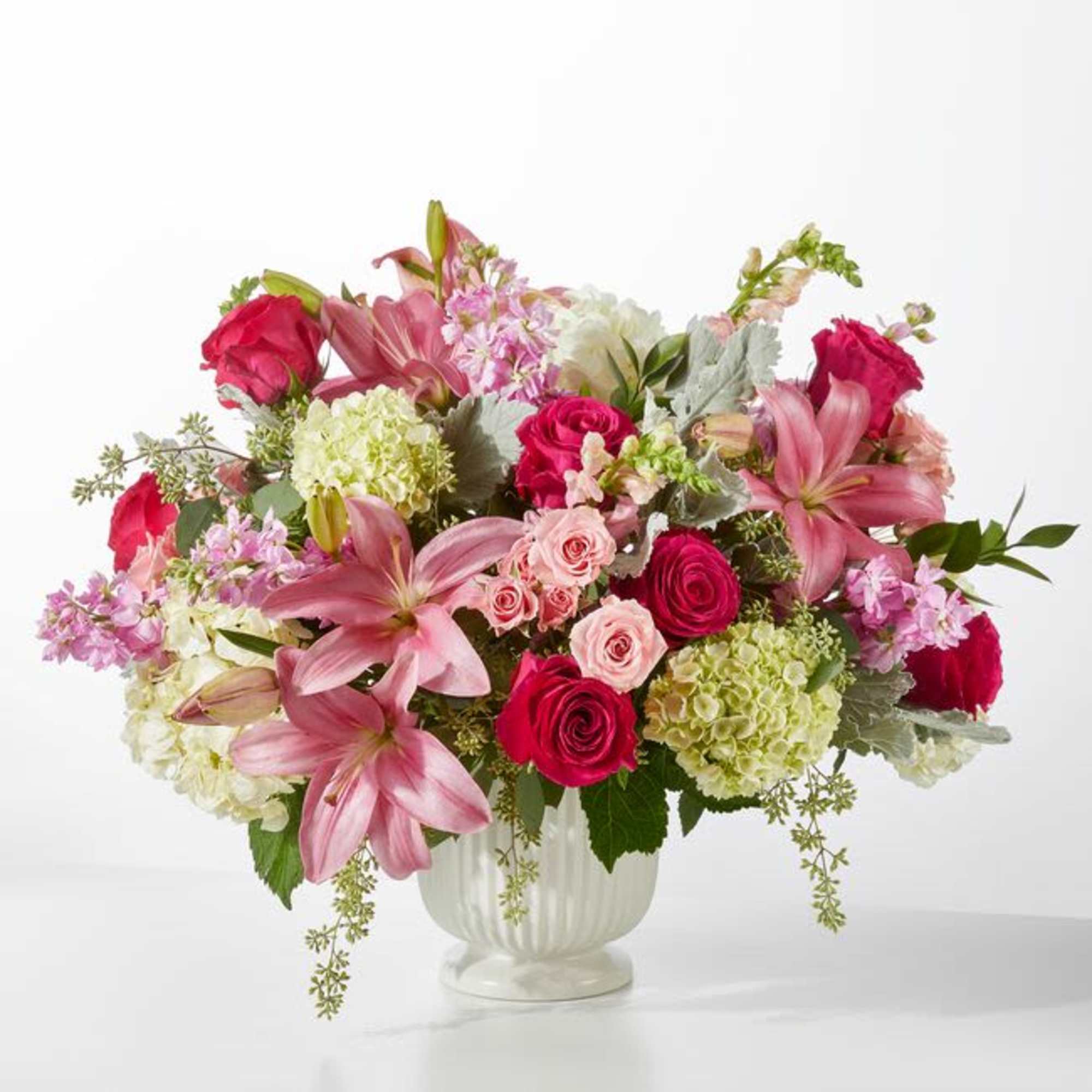 Pink lilies, roses, hydrangeas and lavender stock in a white ceramic vase-lush