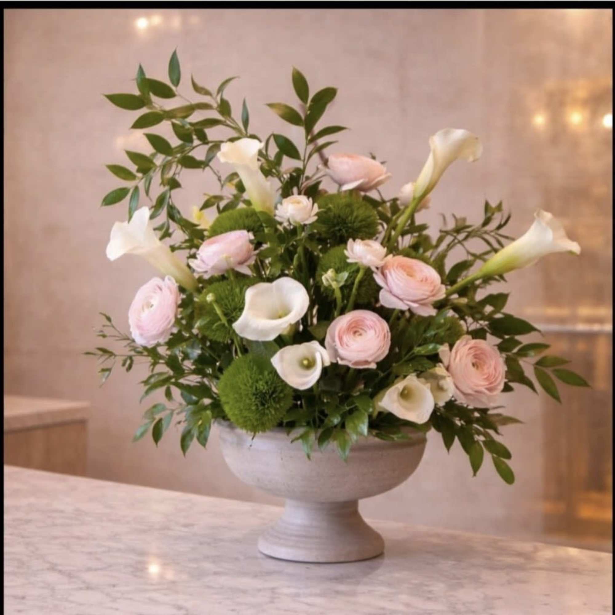 Soft white calla lilies and soft pink ranunculus float above round green