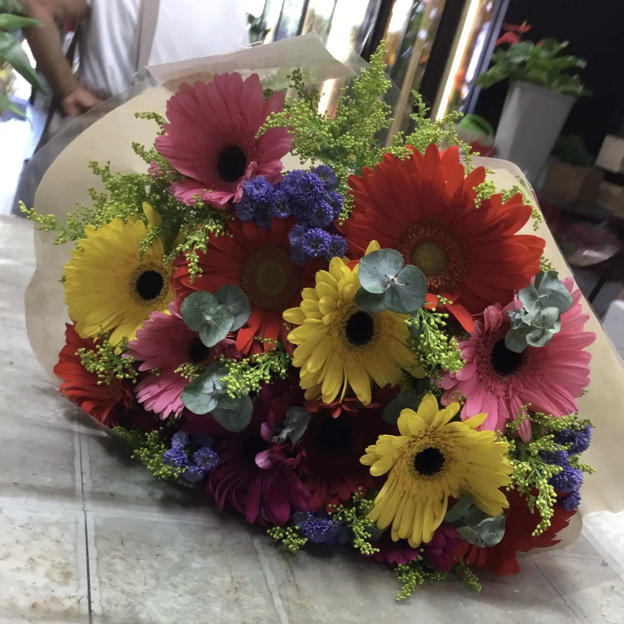 Bouquet of colorful gerbera daisies with greenery and paper wrap