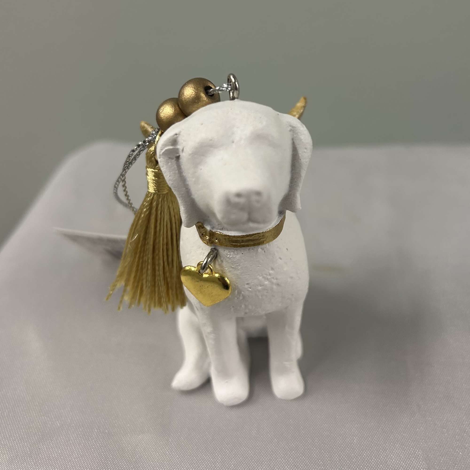 Small white dog figurine ornament with gold tassel and heart charm