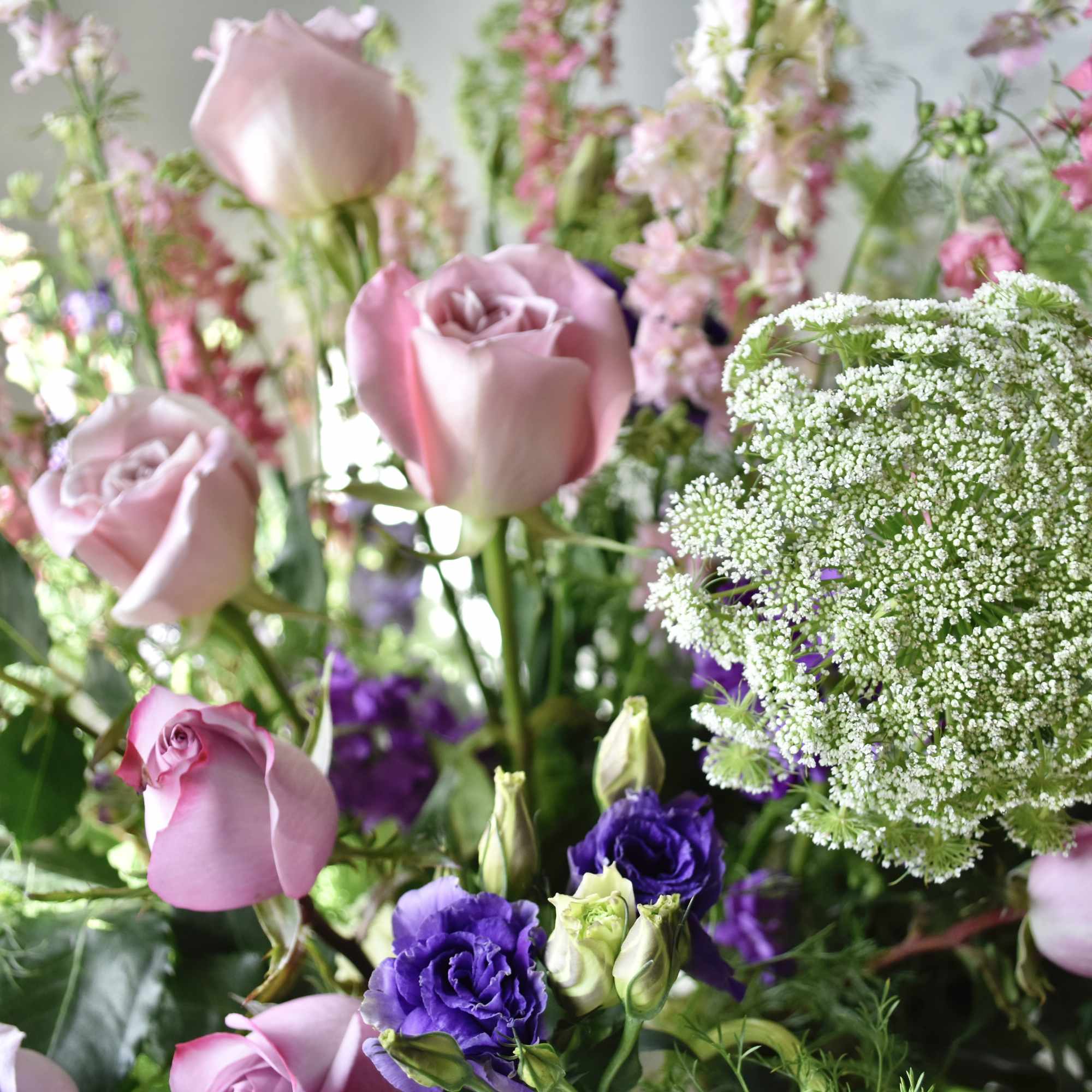 Pink roses and purple blooms with a white lace flower cluster