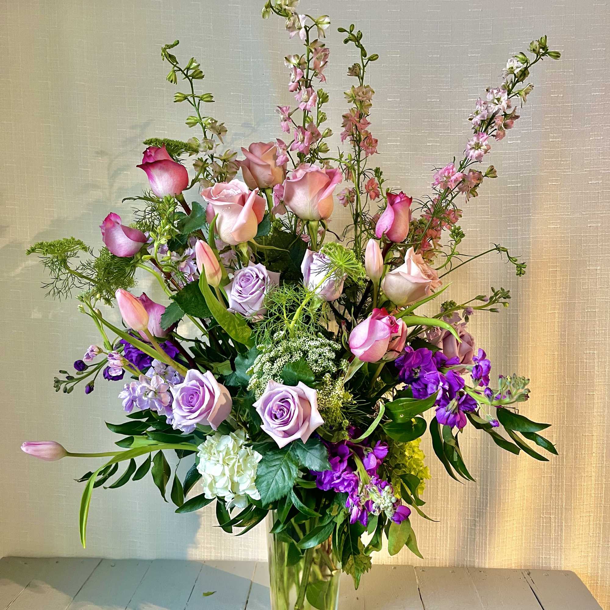 Tall bouquet of pink and lavender roses in a clear glass vase