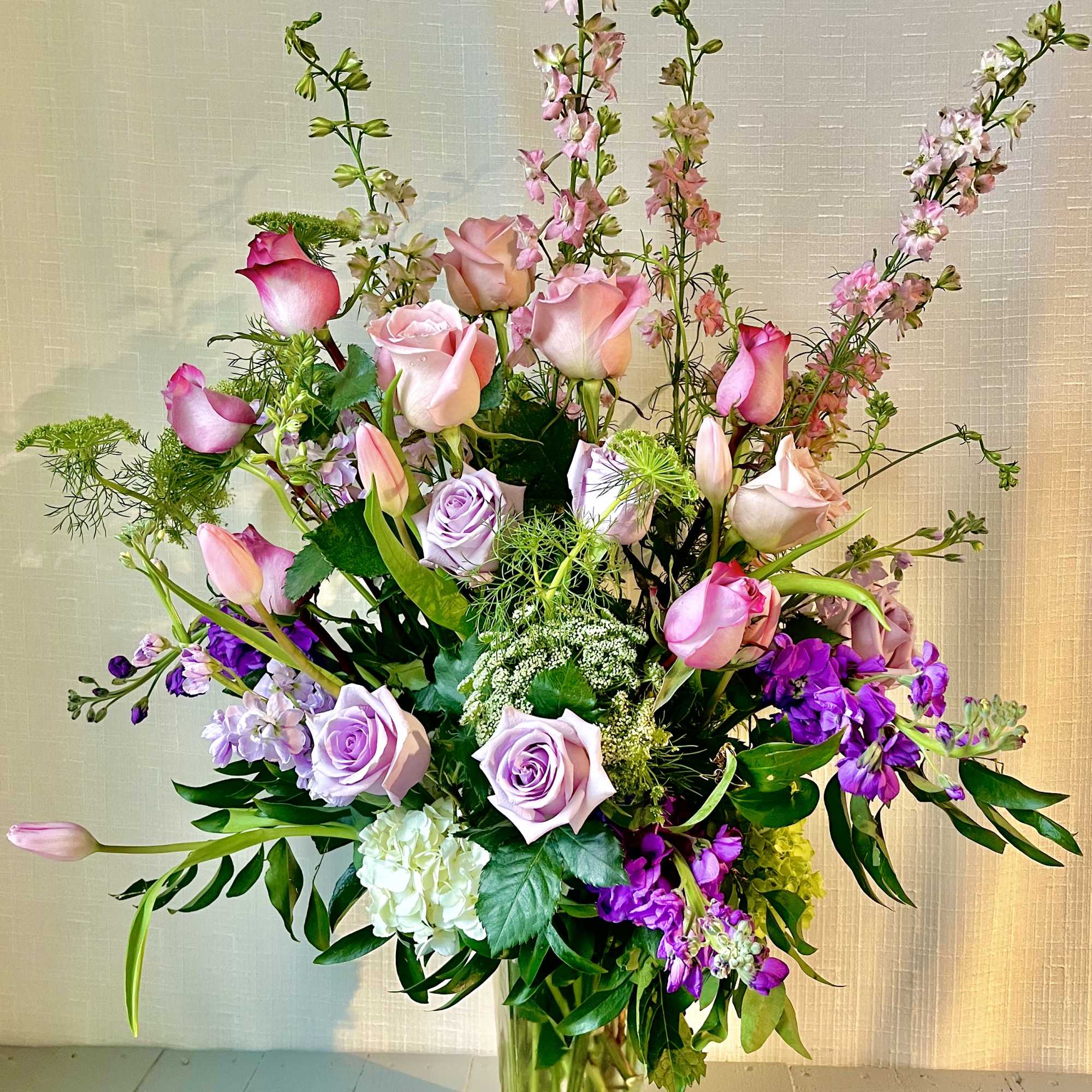 Tall bouquet of pink and lavender roses in a clear glass vase