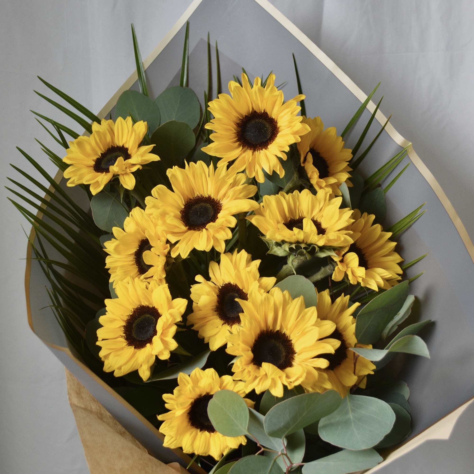 Bouquet of yellow sunflowers wrapped in gray paper