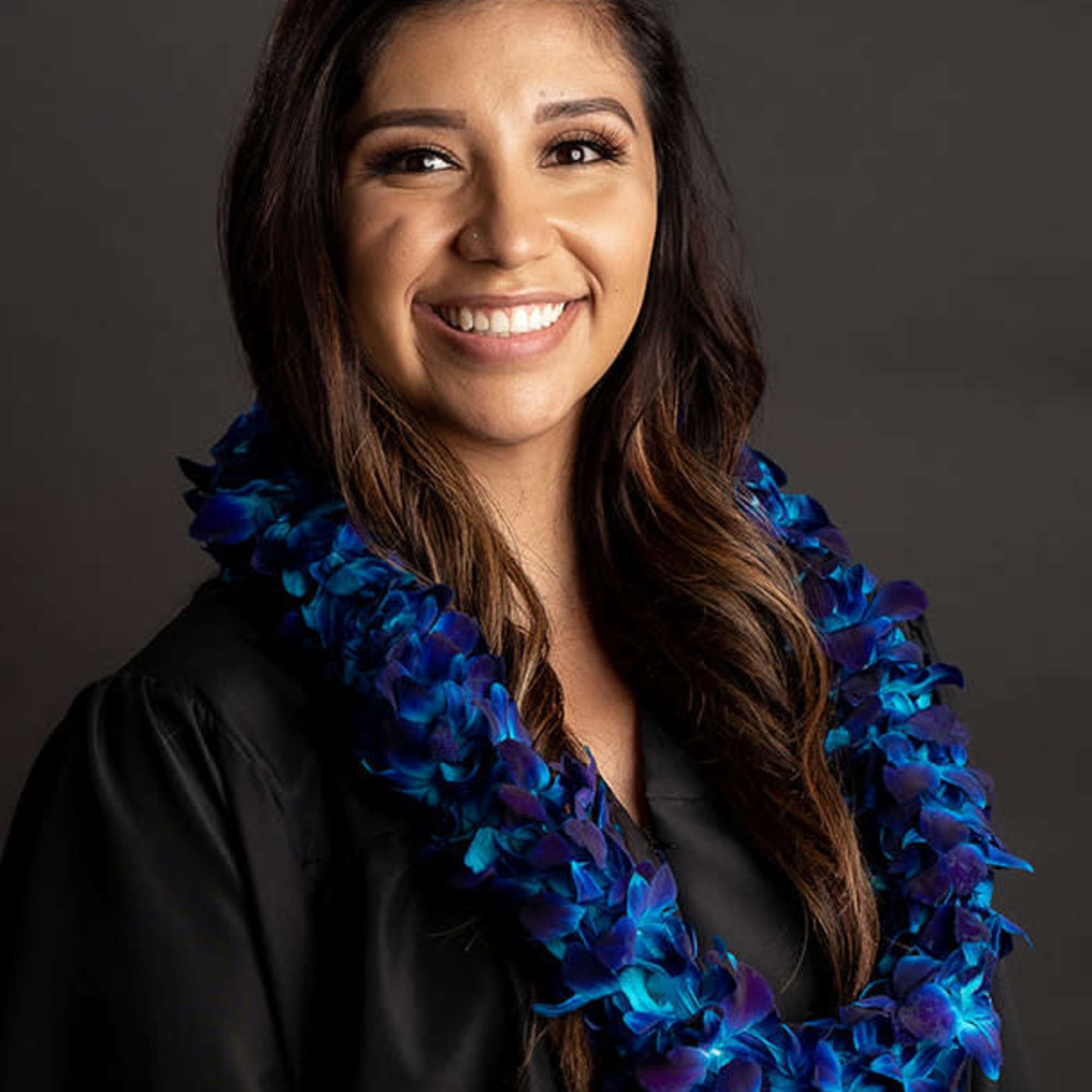 Woman wearing a blue and purple flower lei over a black top