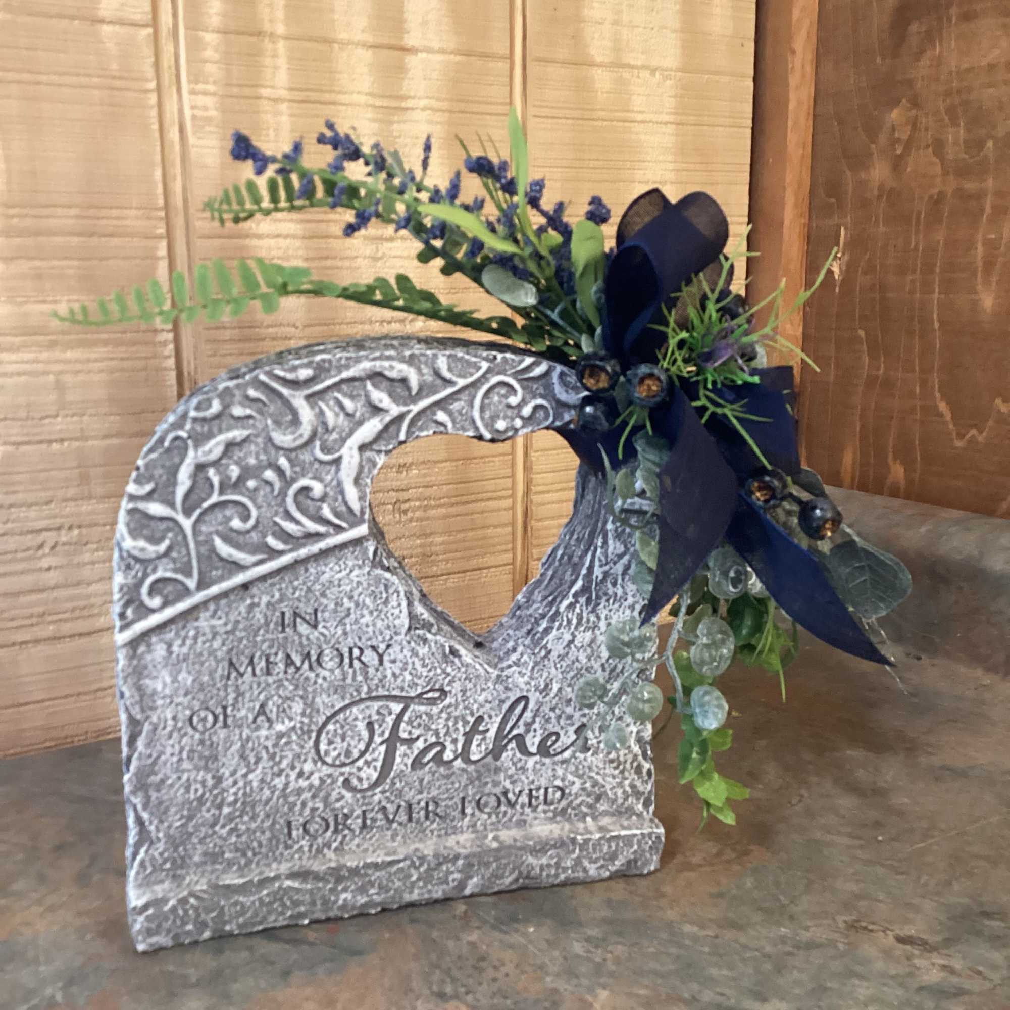 Memorial stone with a small blue floral spray and ribbon