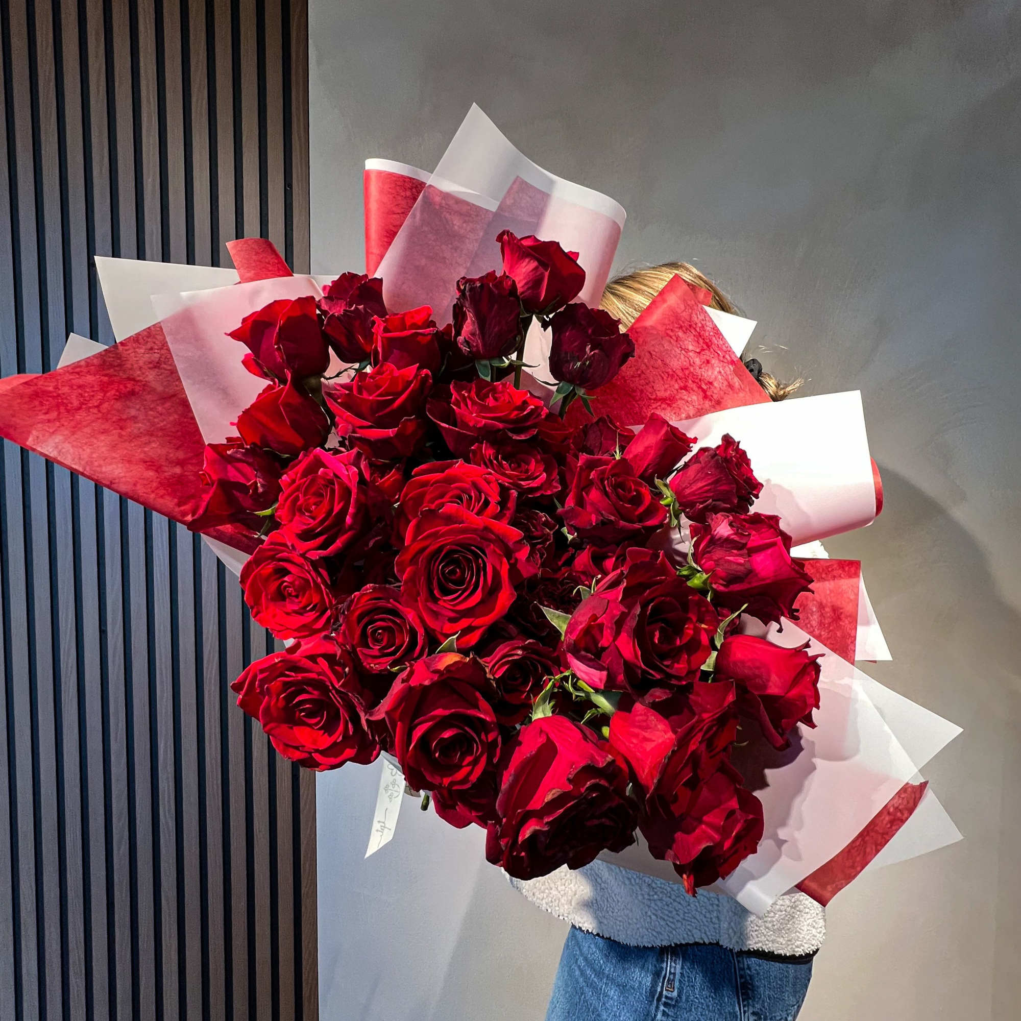 Large bouquet of red roses wrapped in red and white paper