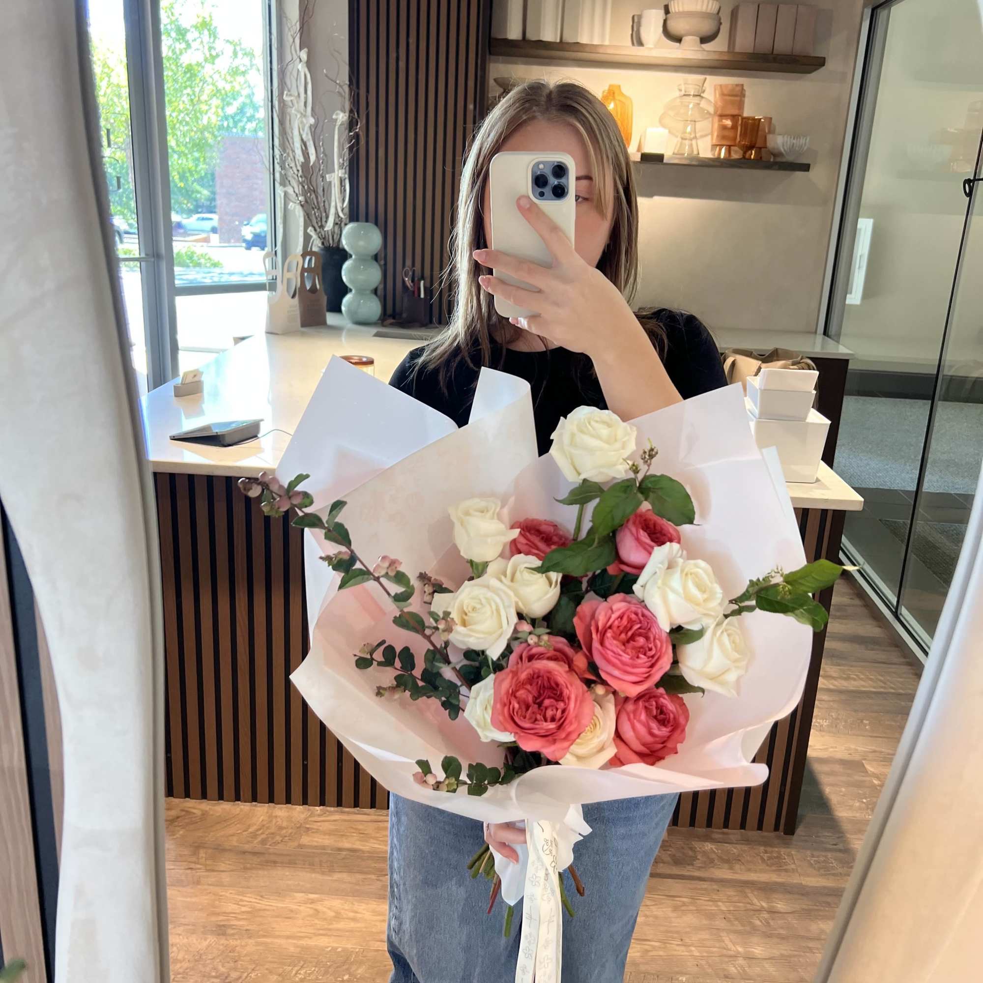 Person holding a bouquet of pink and white roses wrapped in white paper