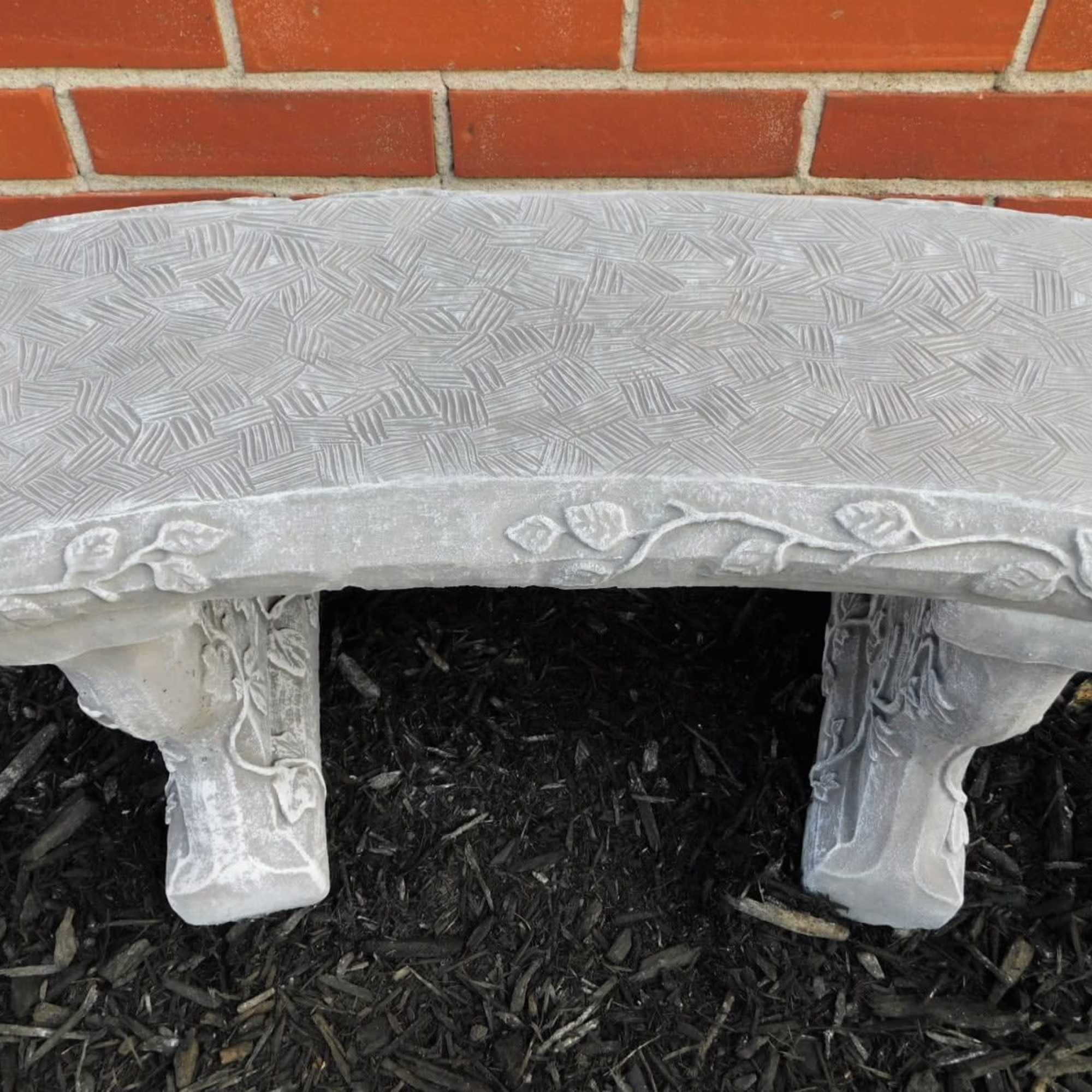 Decorative stone garden bench against a brick wall